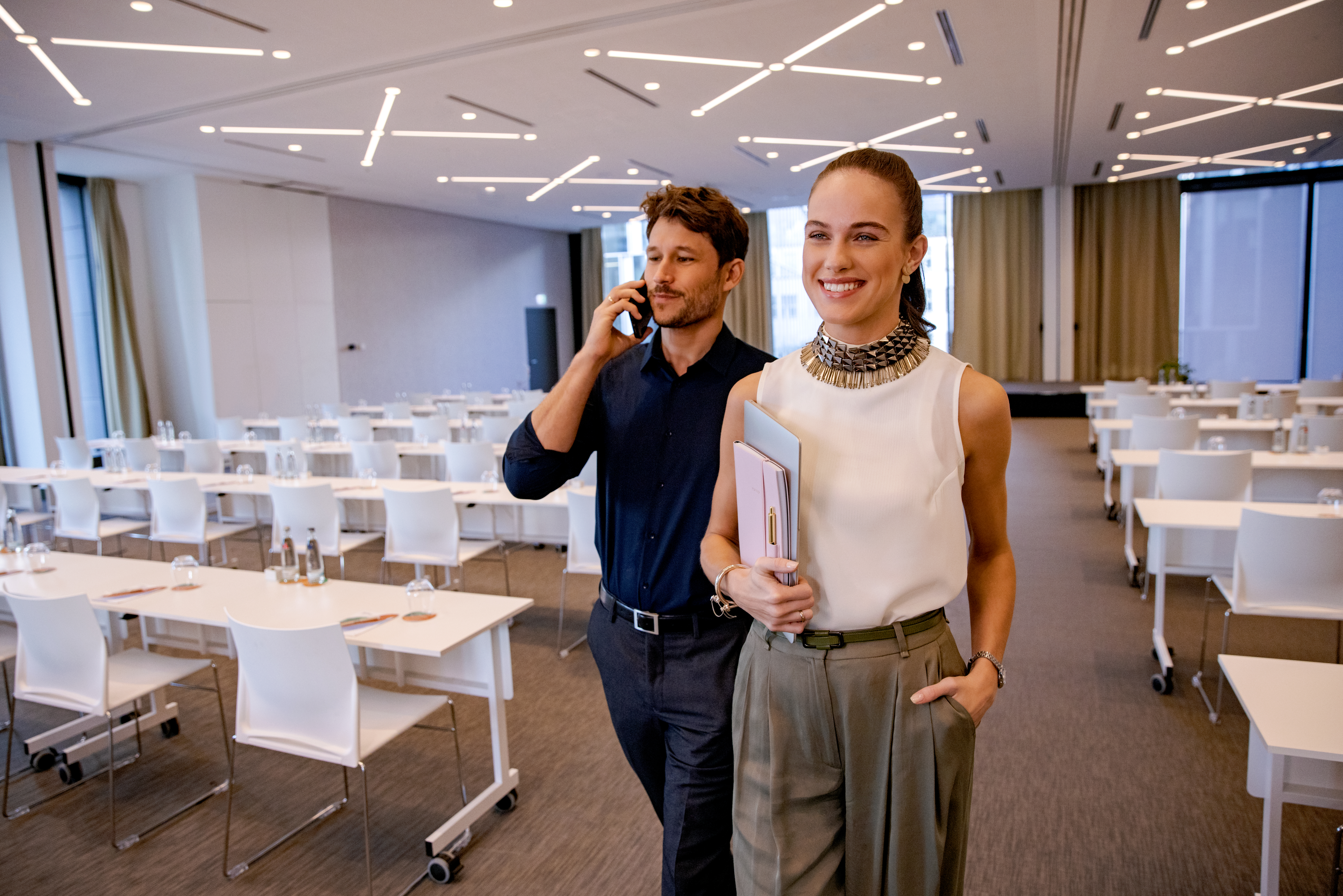 a man and woman standing in a room with tables and chairs