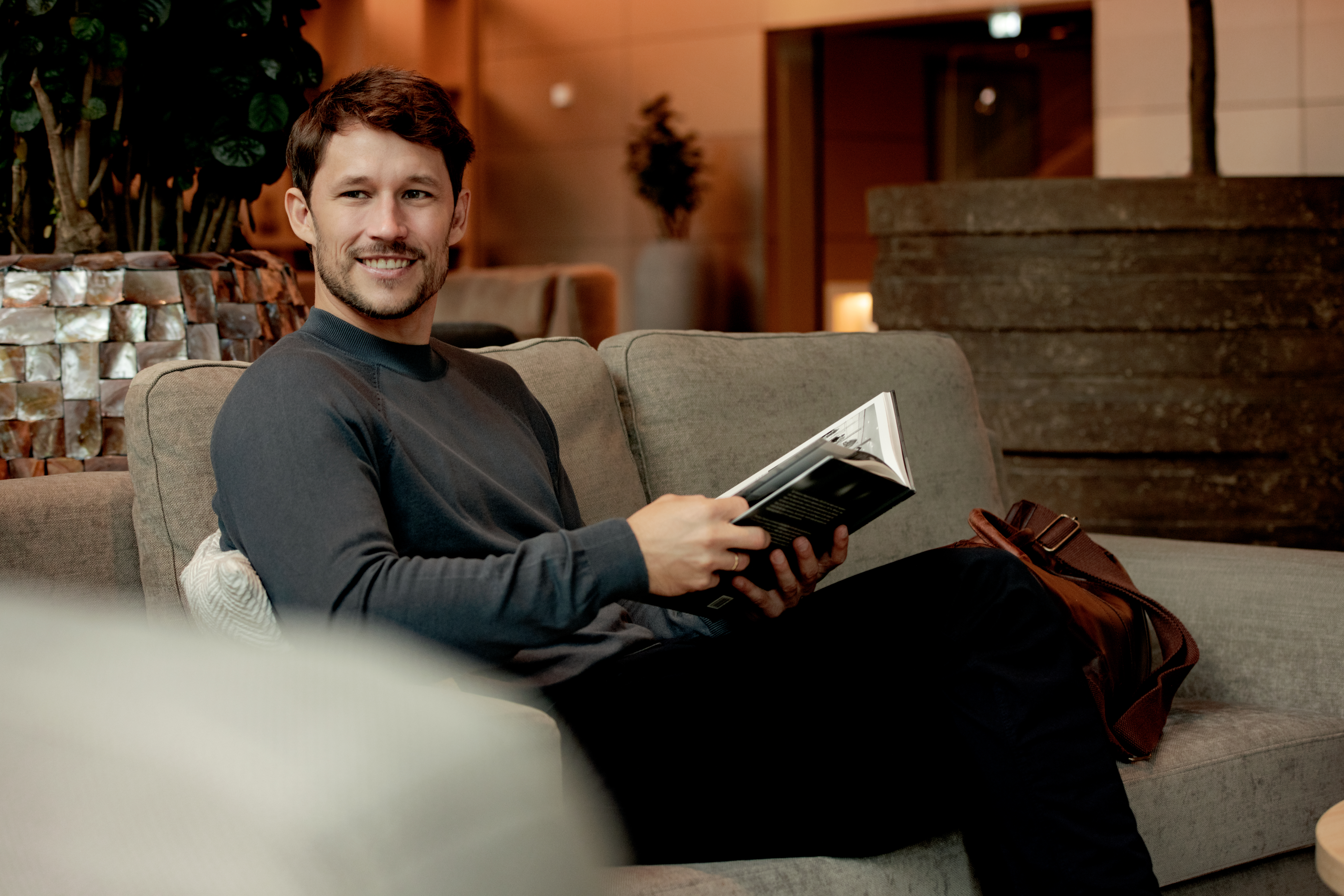 a man sitting on a couch holding a book