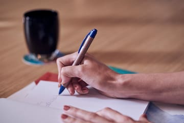 a hand holding a pen and writing on a piece of paper