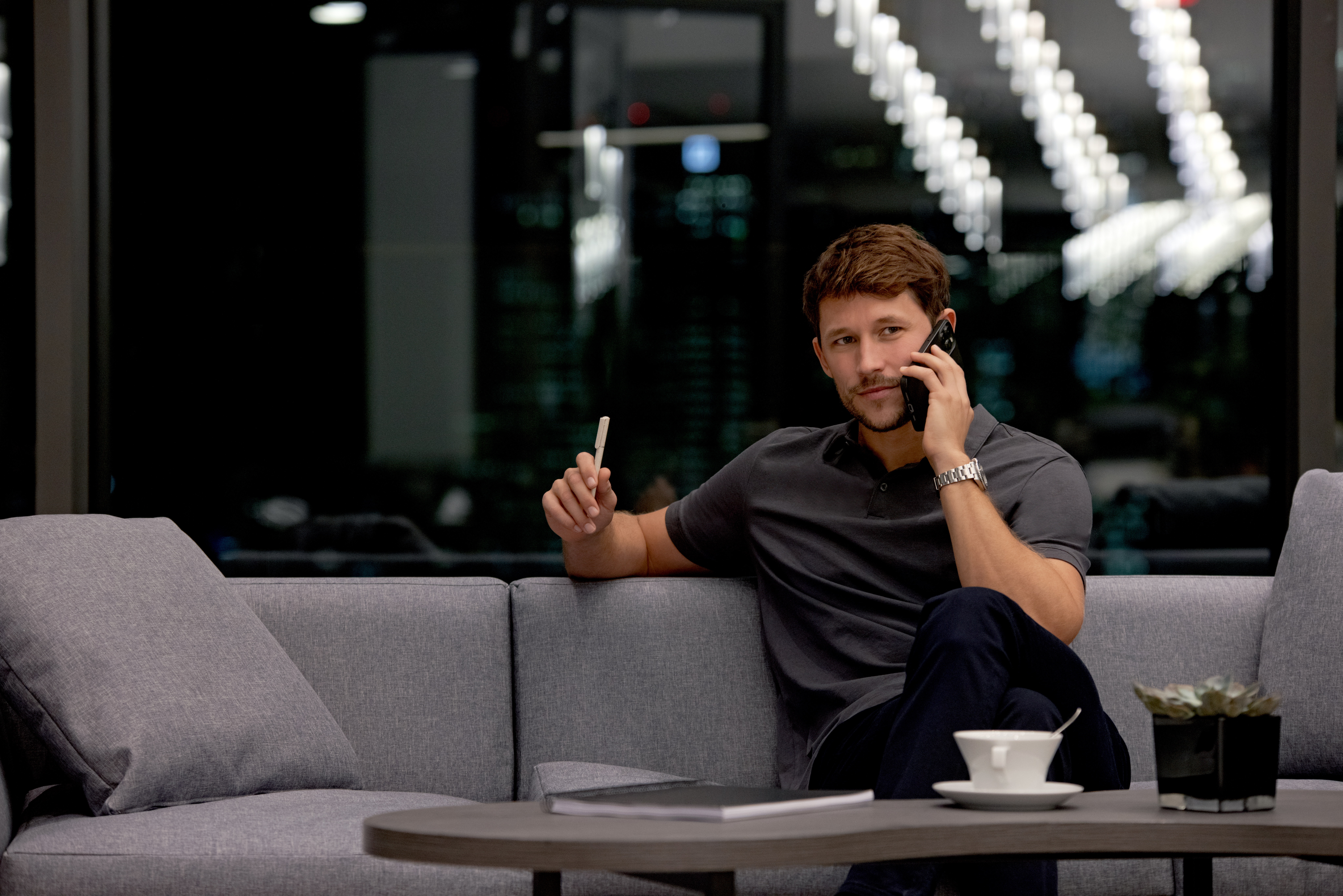 a man sitting on a couch talking on a cell phone