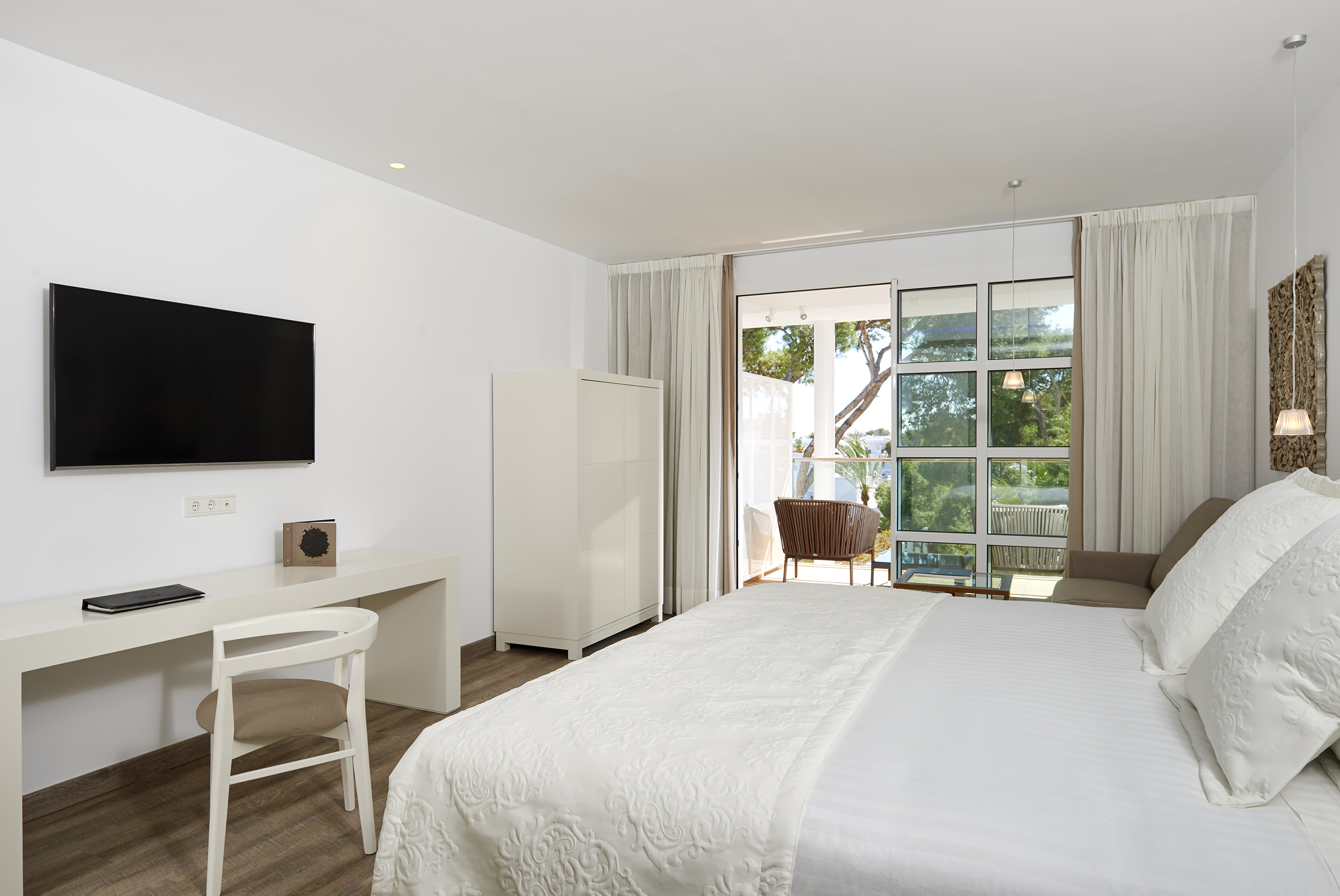 Bright modern hotel bedroom with a large bed, TV, and balcony access.