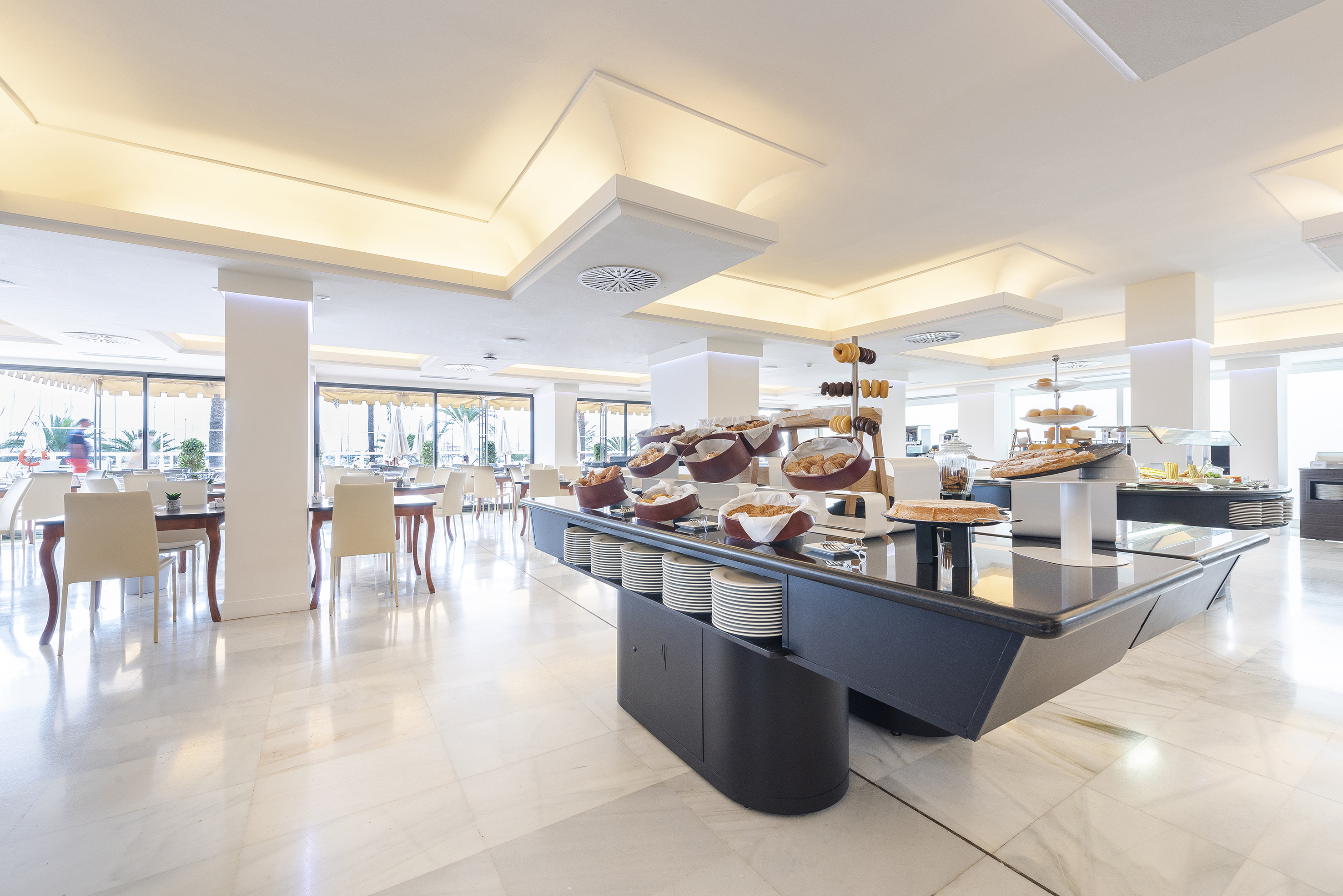 Bright hotel breakfast buffet with pastries and a modern dining area.