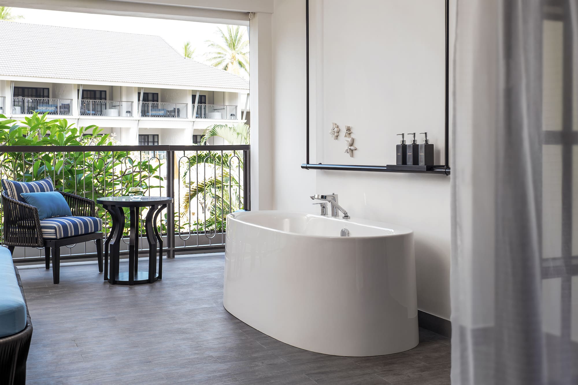 a white bathtub in a room with a balcony and a window