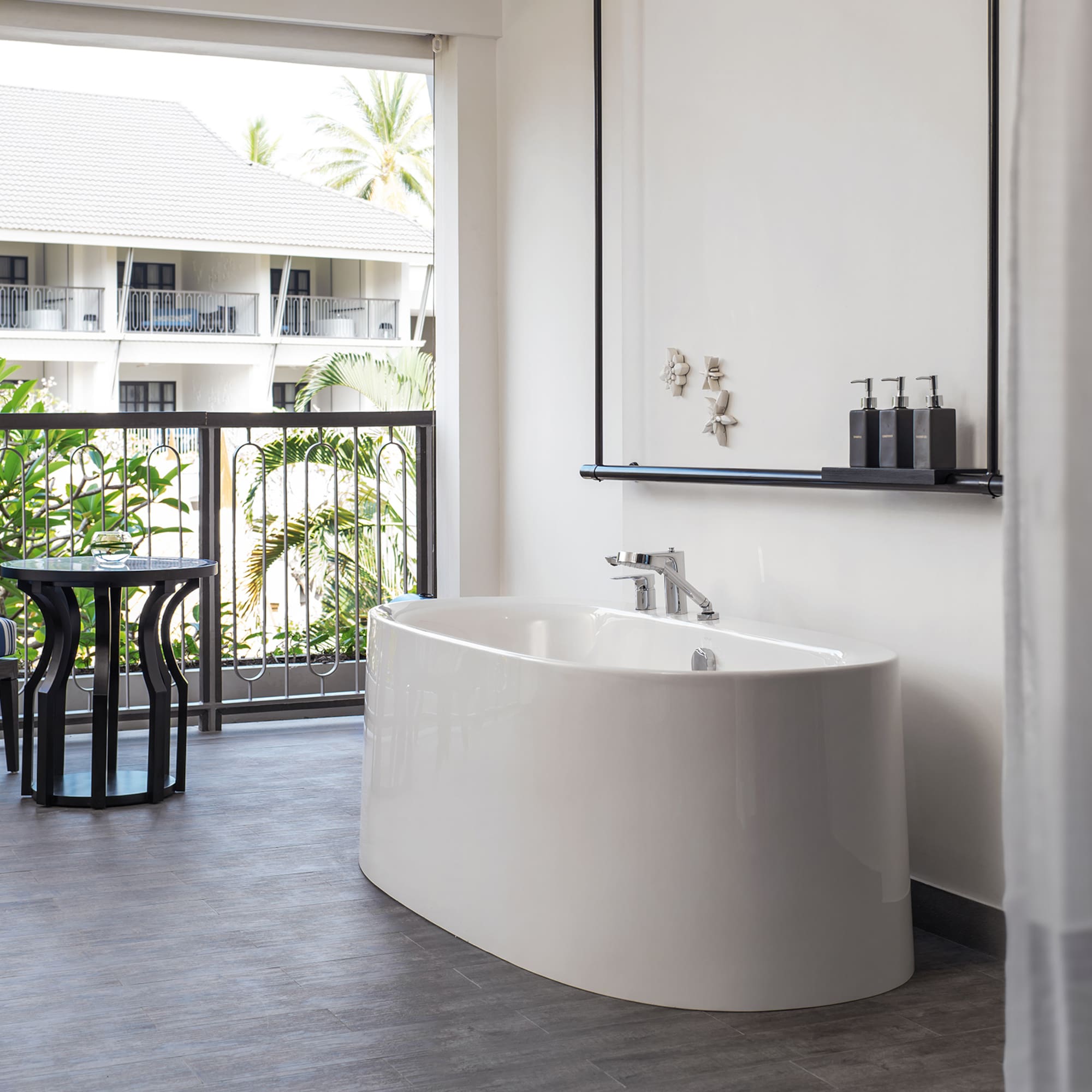 a white bathtub in a room with a balcony and a window
