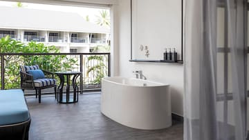 a white bathtub in a room with a balcony and a window
