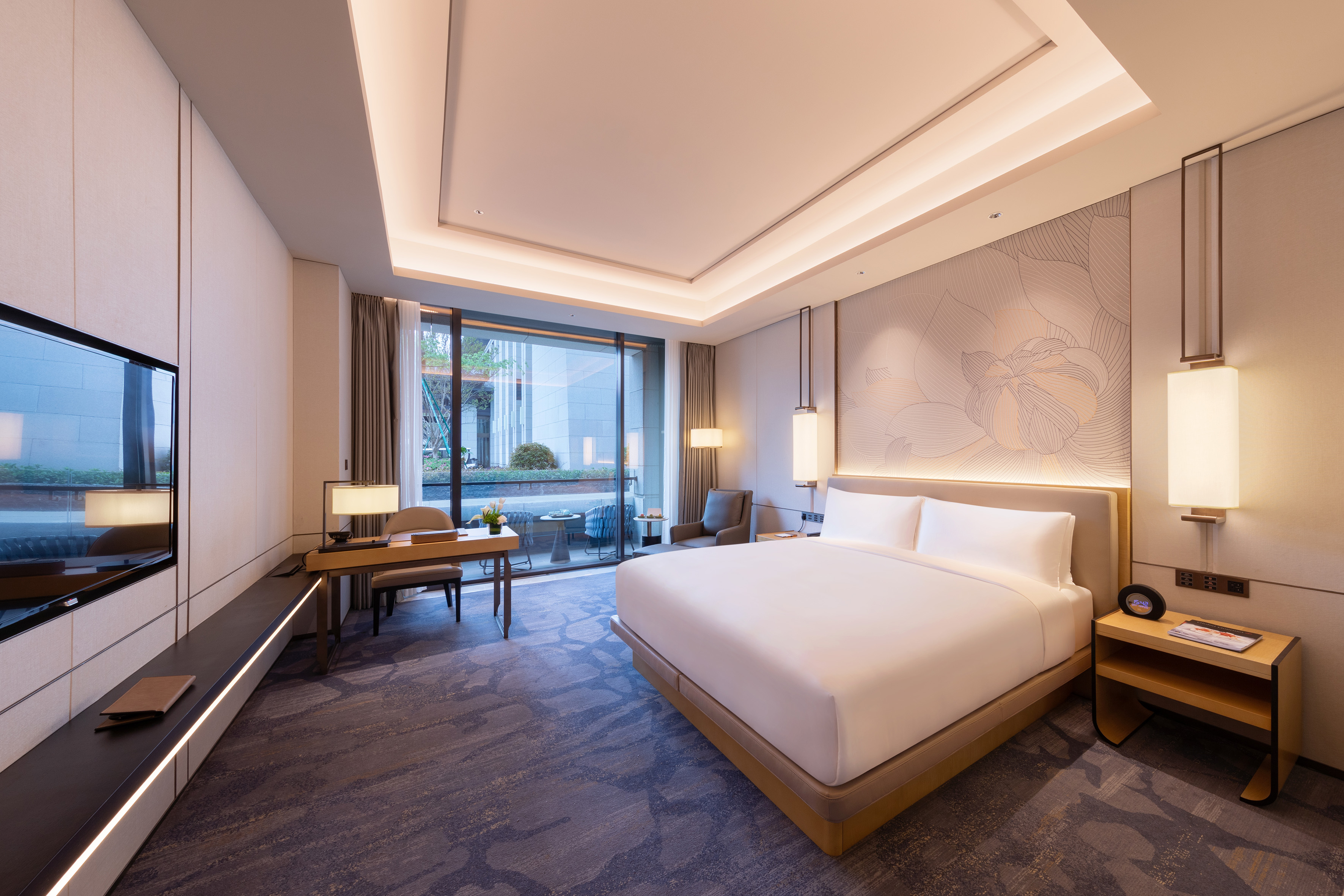 Luxury hotel bedroom with king bed, work desk, and balcony access.