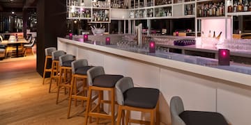 a bar with chairs and a shelf with wine glasses