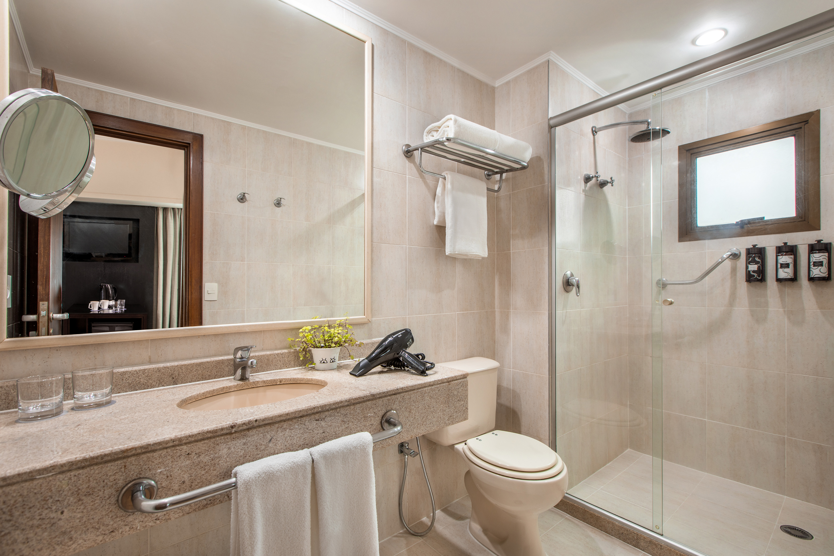 Bright, clean hotel bathroom with shower, toilet, vanity, and mirror.