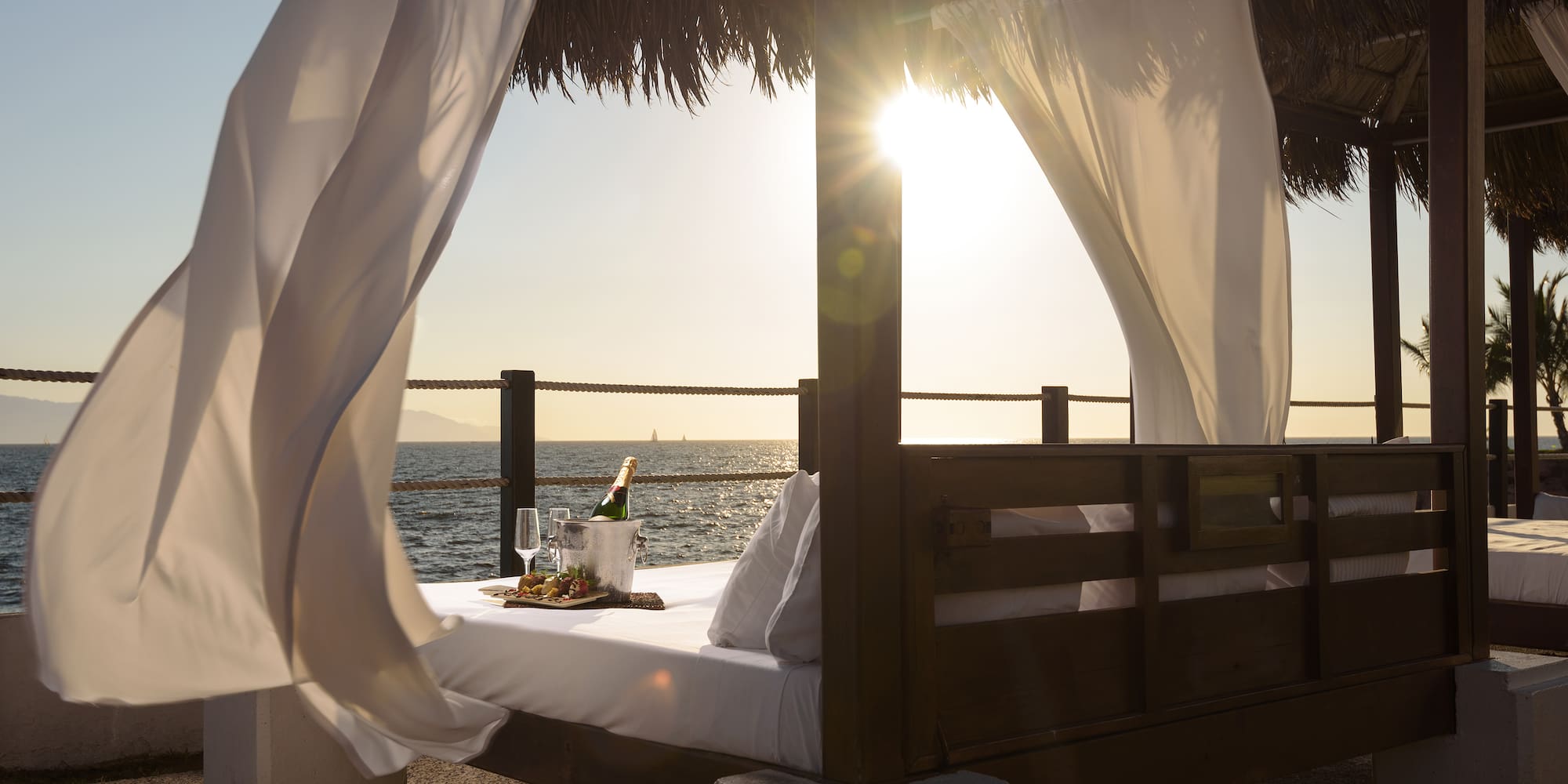 a bed with a tray of wine and a tray of wine on a beach