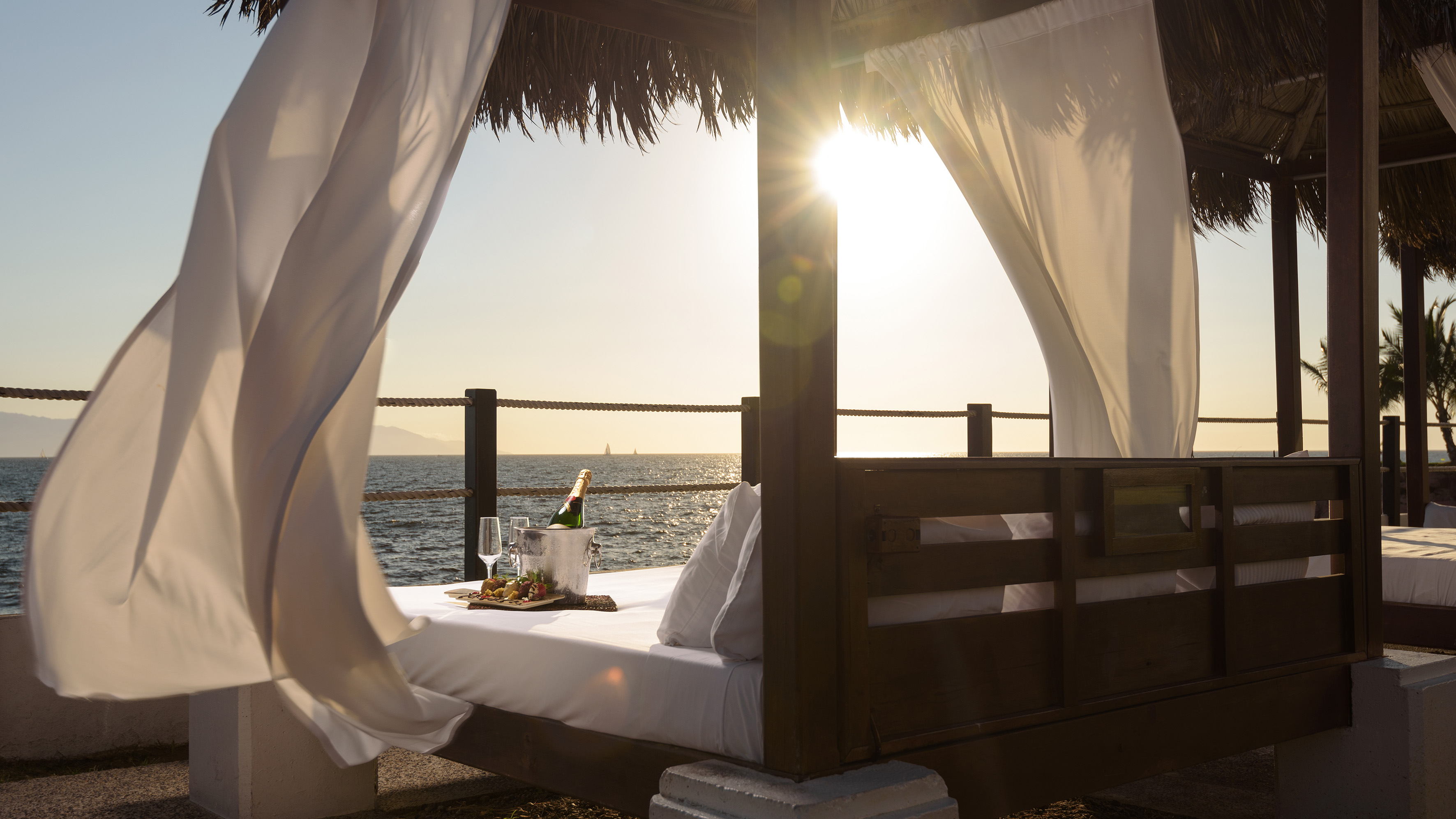 a bed with a tray of wine and a tray of wine on a beach