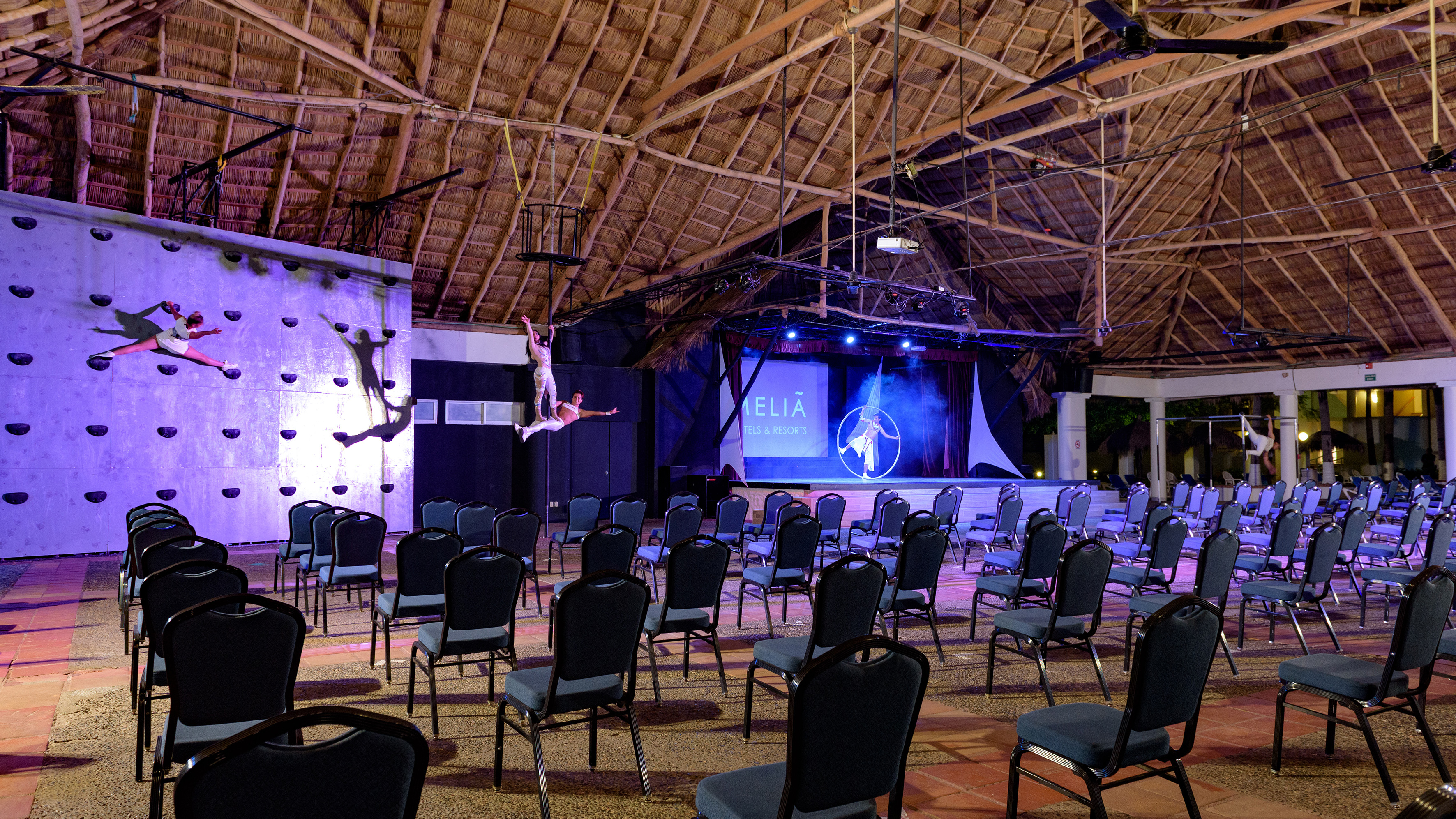 Meliã resort aerial show with acrobats under a thatched roof.