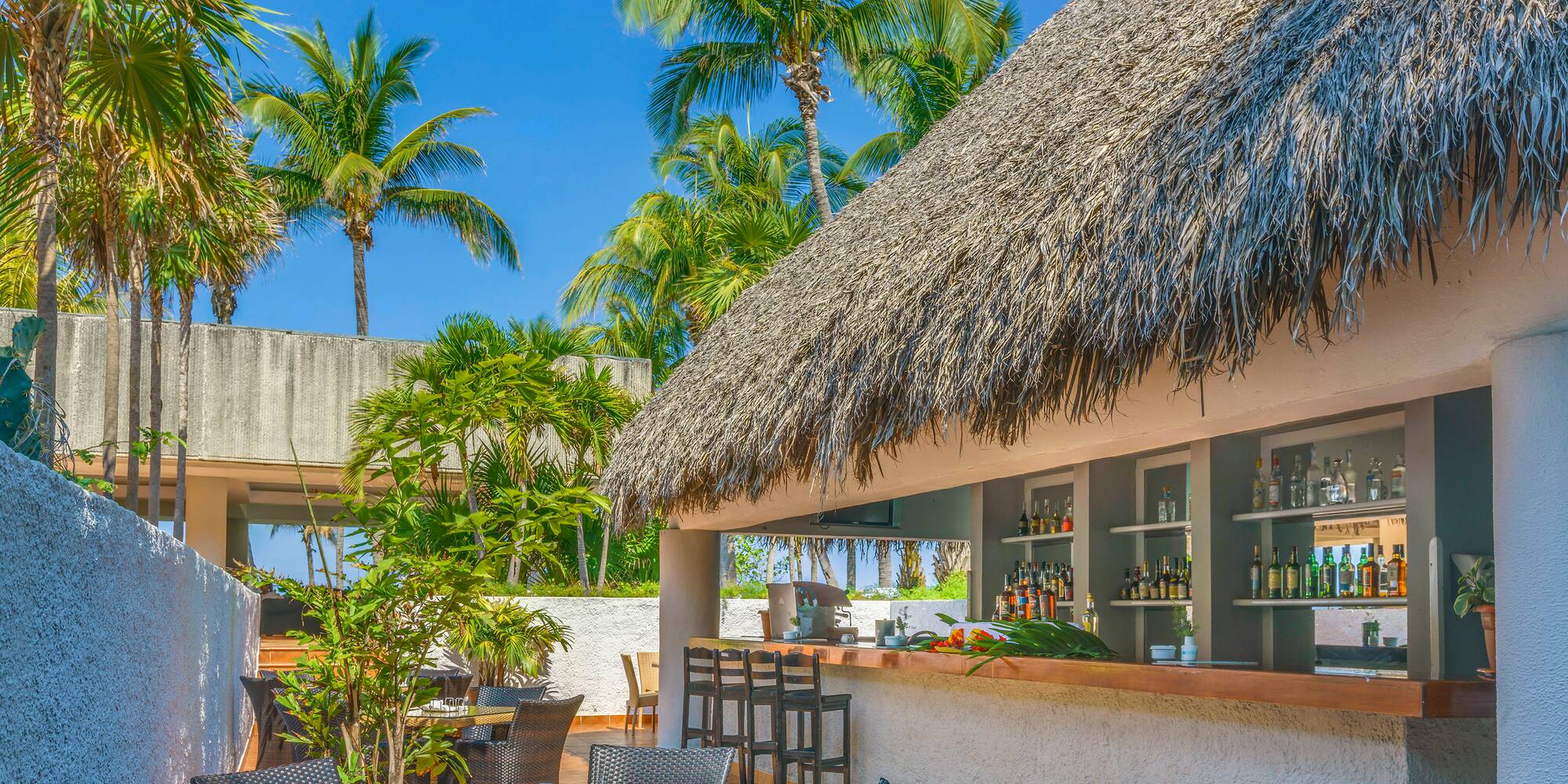a bar with a thatched roof and tables and chairs