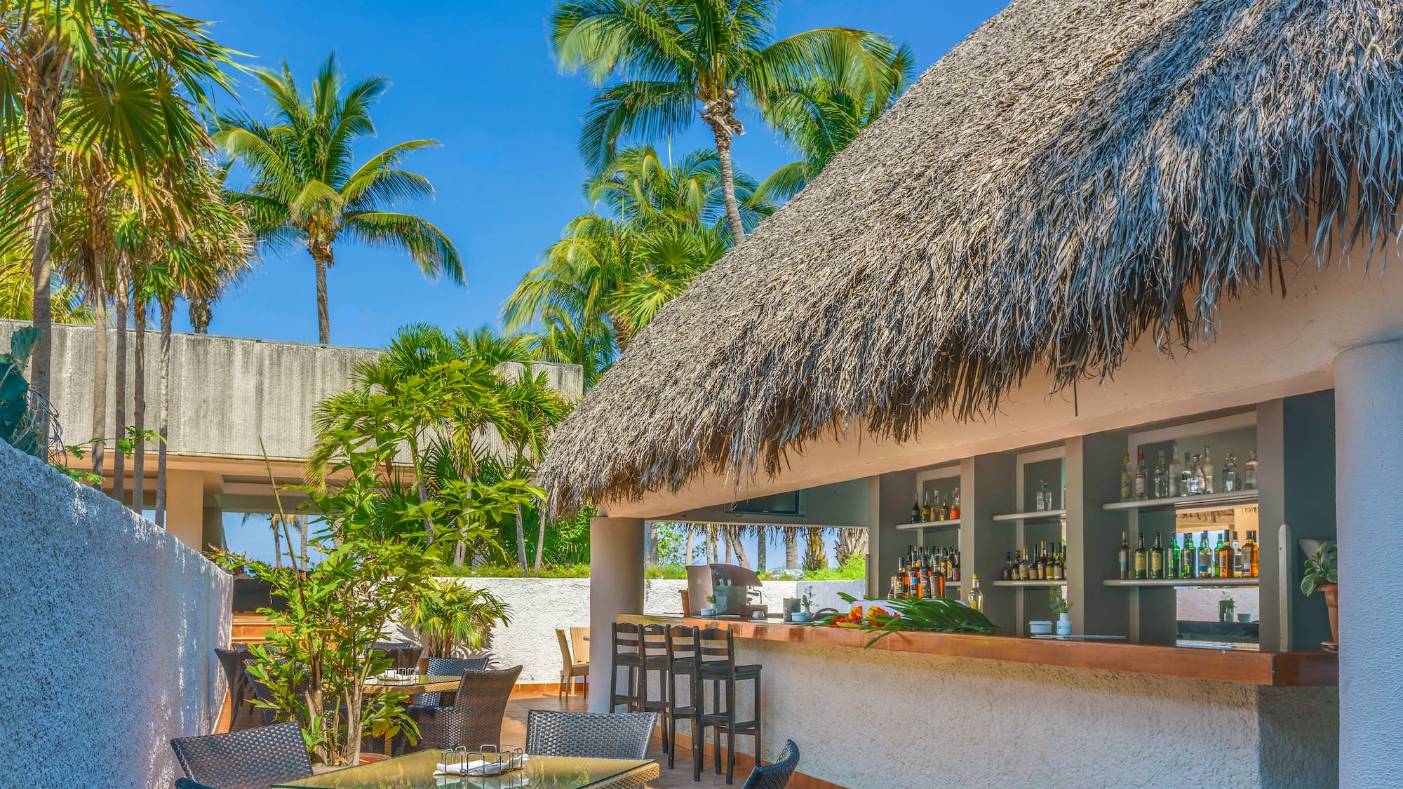 a bar with a thatched roof and tables and chairs