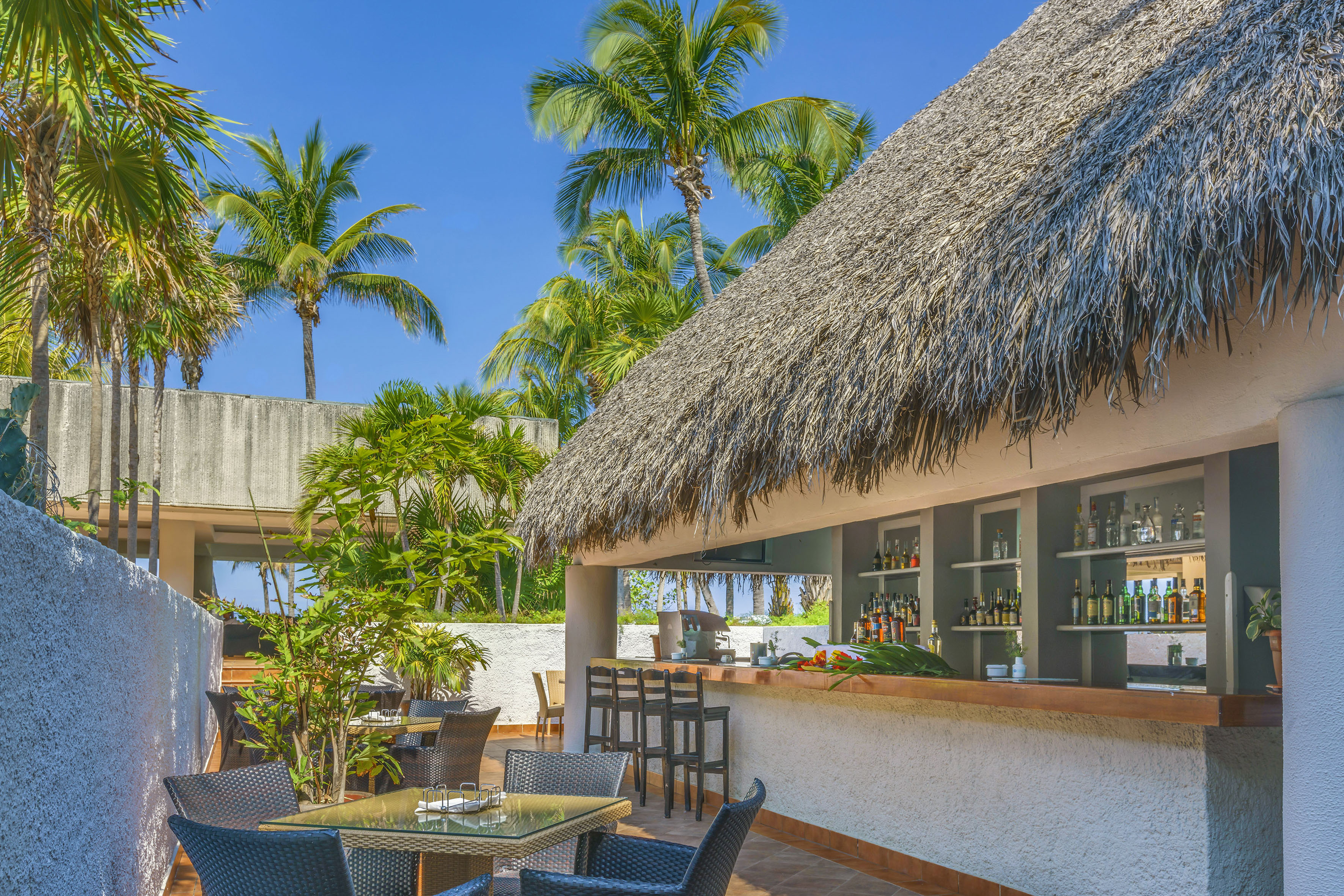 a bar with a thatched roof and tables and chairs