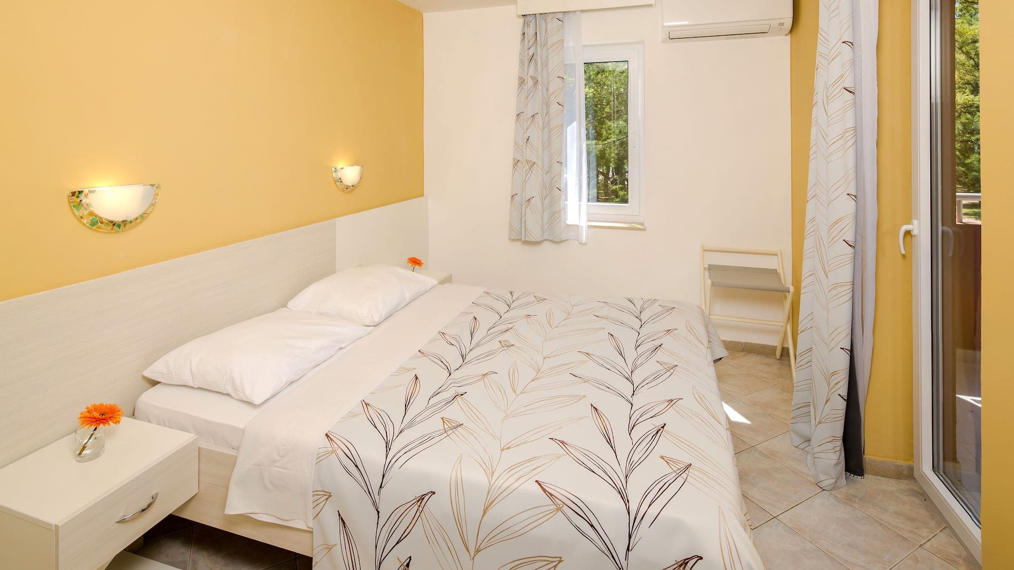 a bed with white sheets and pillows in a room with yellow walls