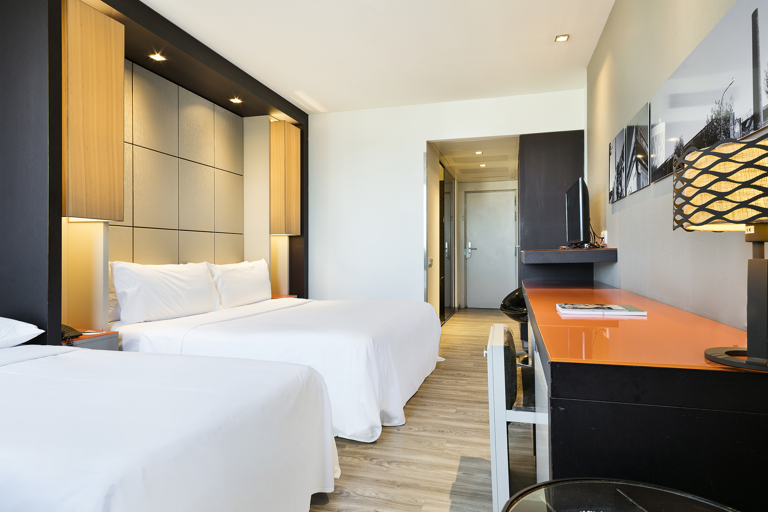 Modern hotel guest room featuring two beds, a desk, and ambient lighting.