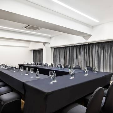 a long conference room with black tablecloths and chairs