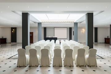 a room with white chairs and a large screen