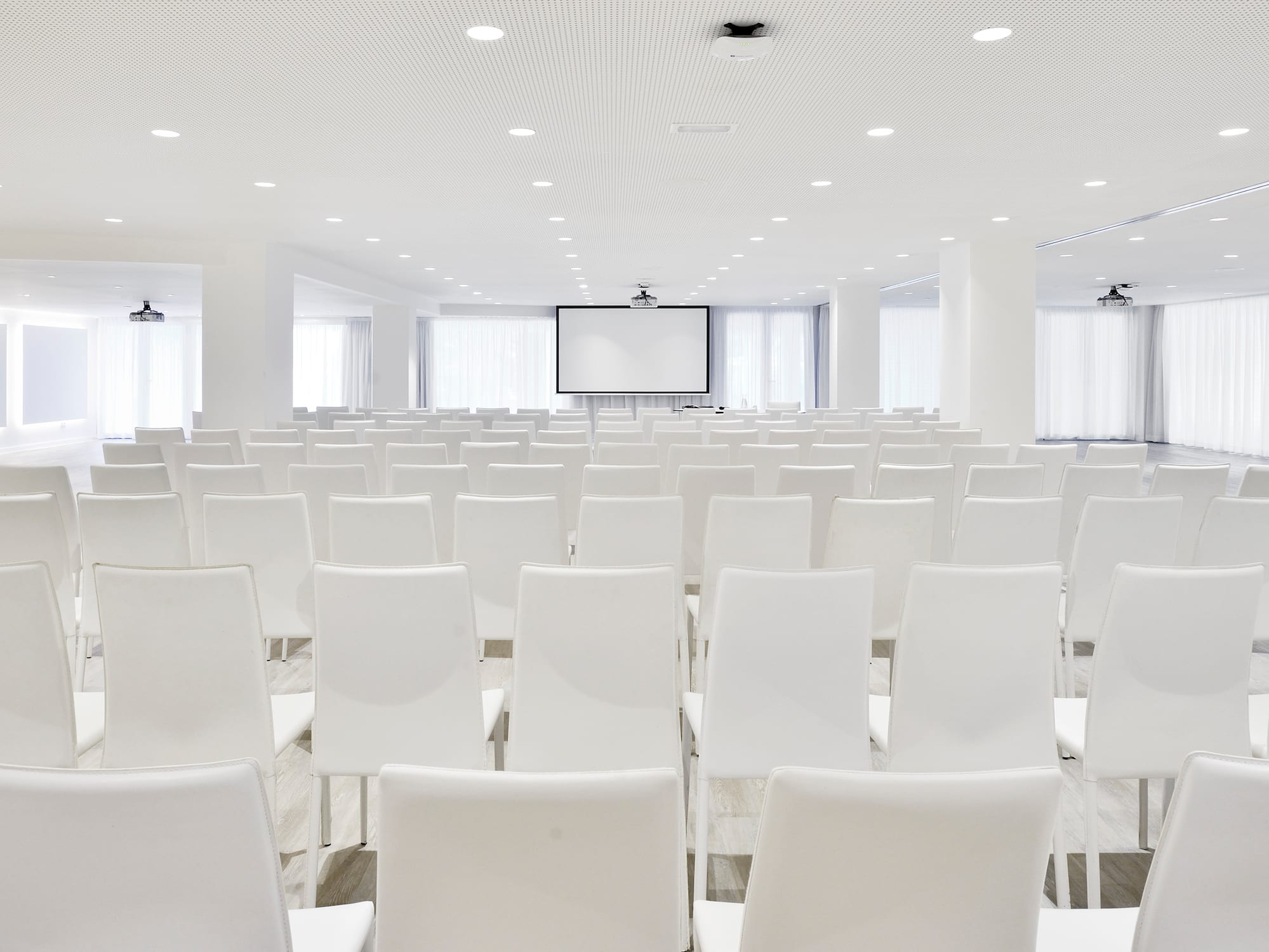 a room with white chairs and a projector screen