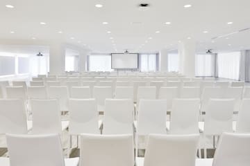 a room with white chairs and a projector screen