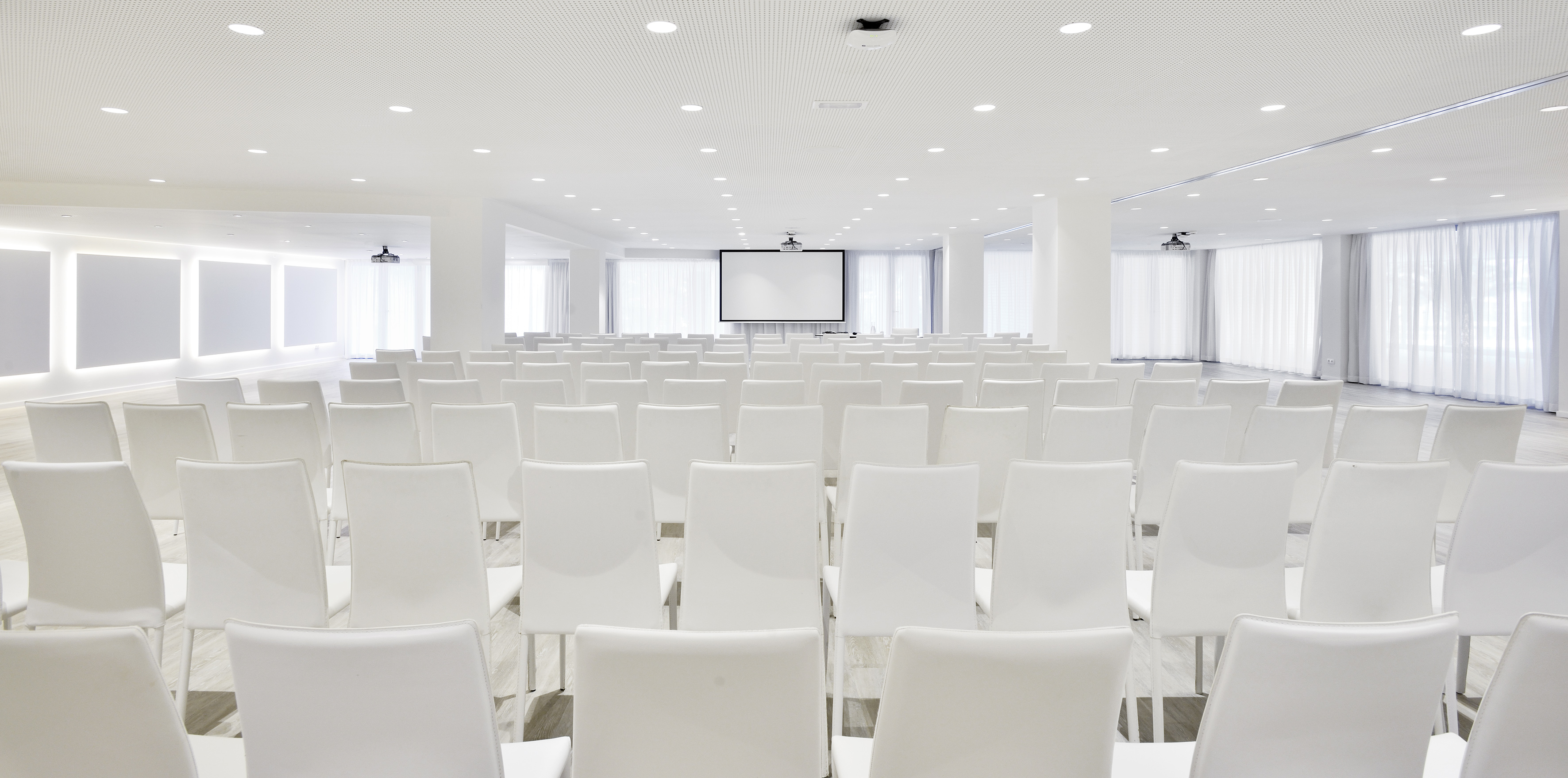 Empty modern conference room with white chairs and large projection screen.