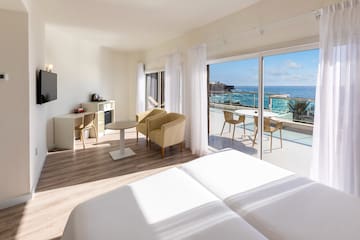 a room with a view of the ocean and a table and chairs