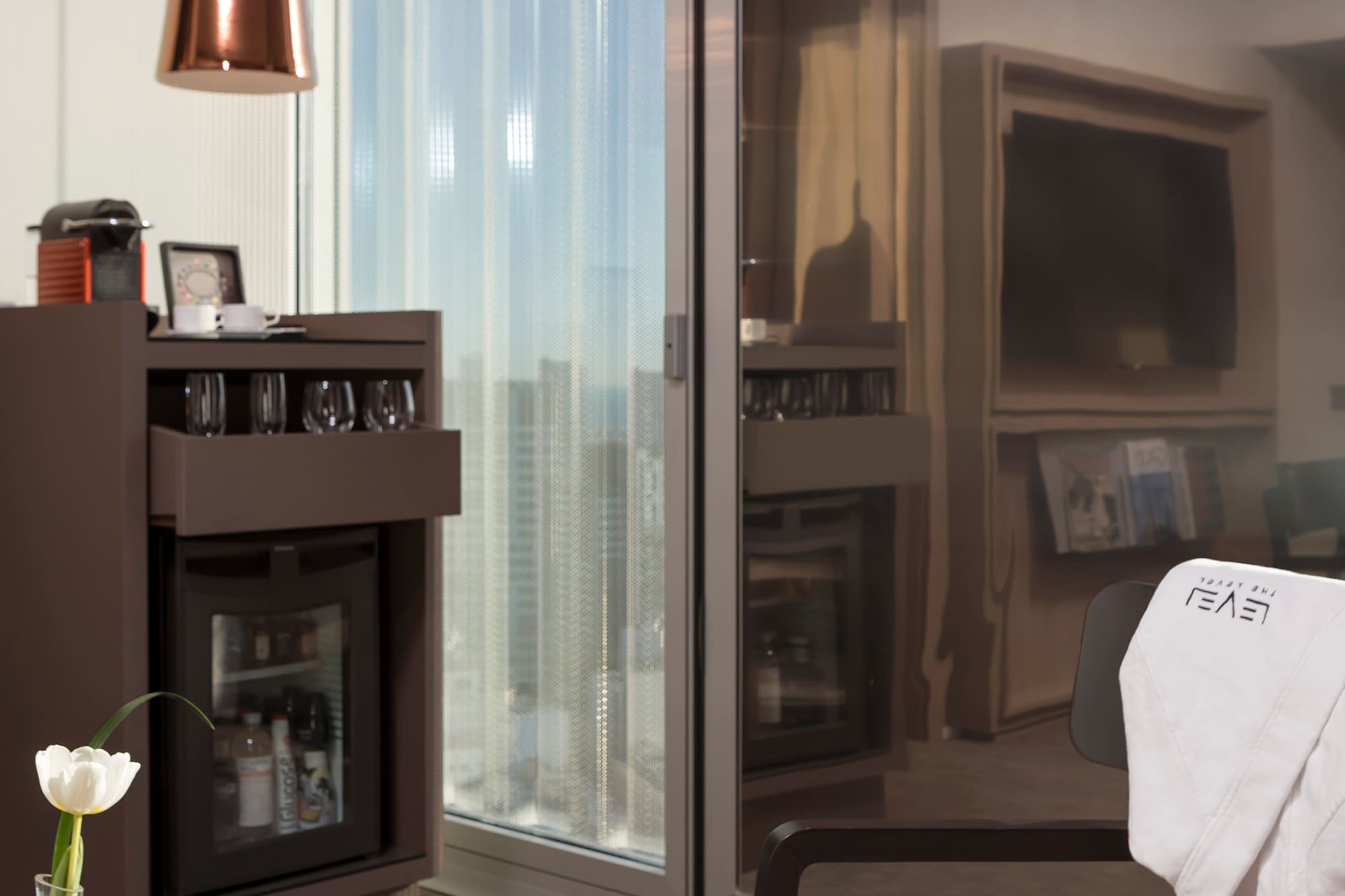 a room with a glass wall and a table with coffee cups and a television