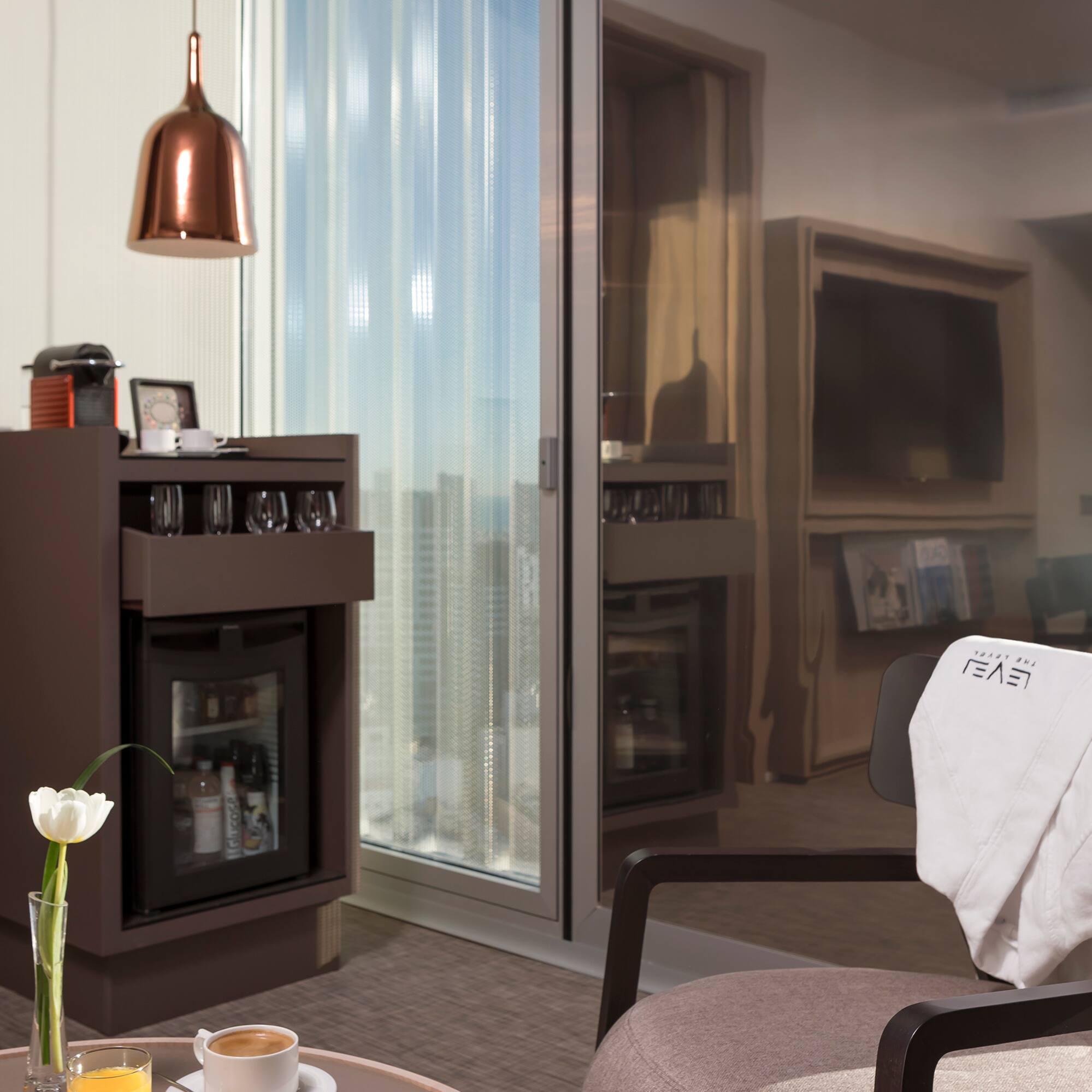 a room with a glass wall and a table with coffee cups and a television