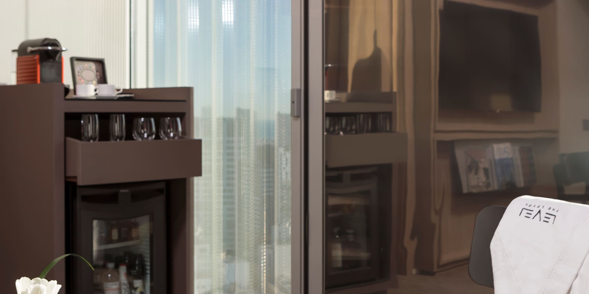 a room with a glass wall and a table with coffee cups and a television