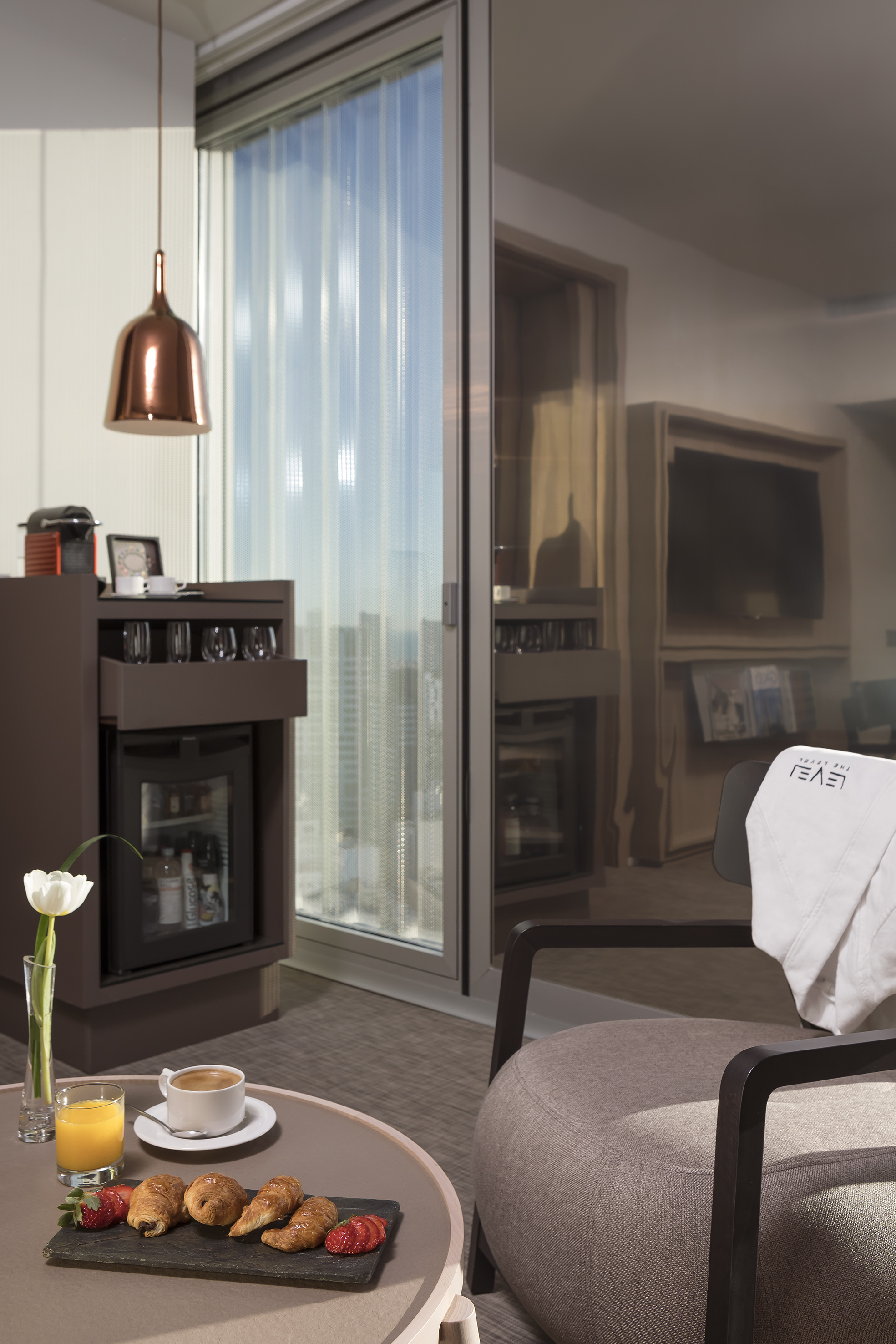 a room with a glass wall and a table with coffee cups and a television