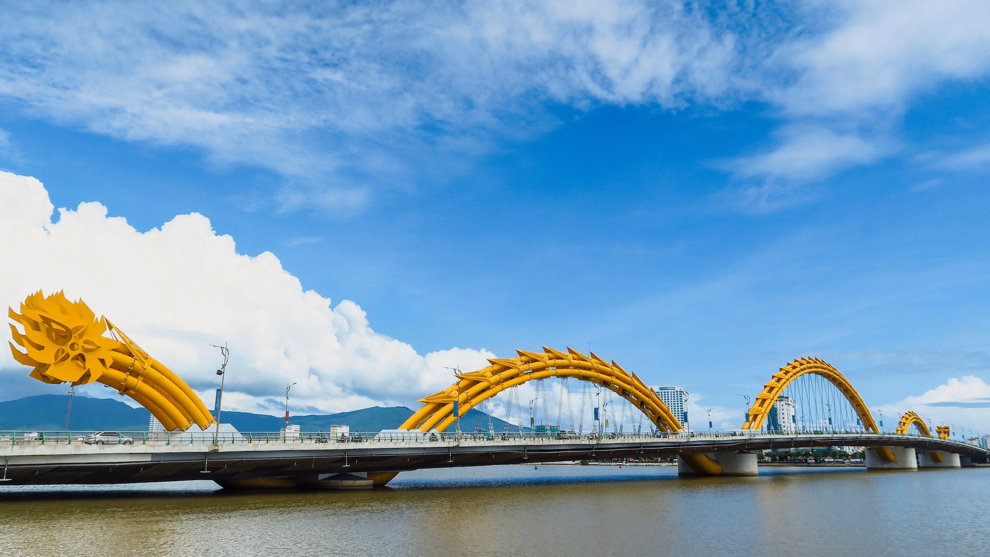 a bridge with a large yellow bridge over water