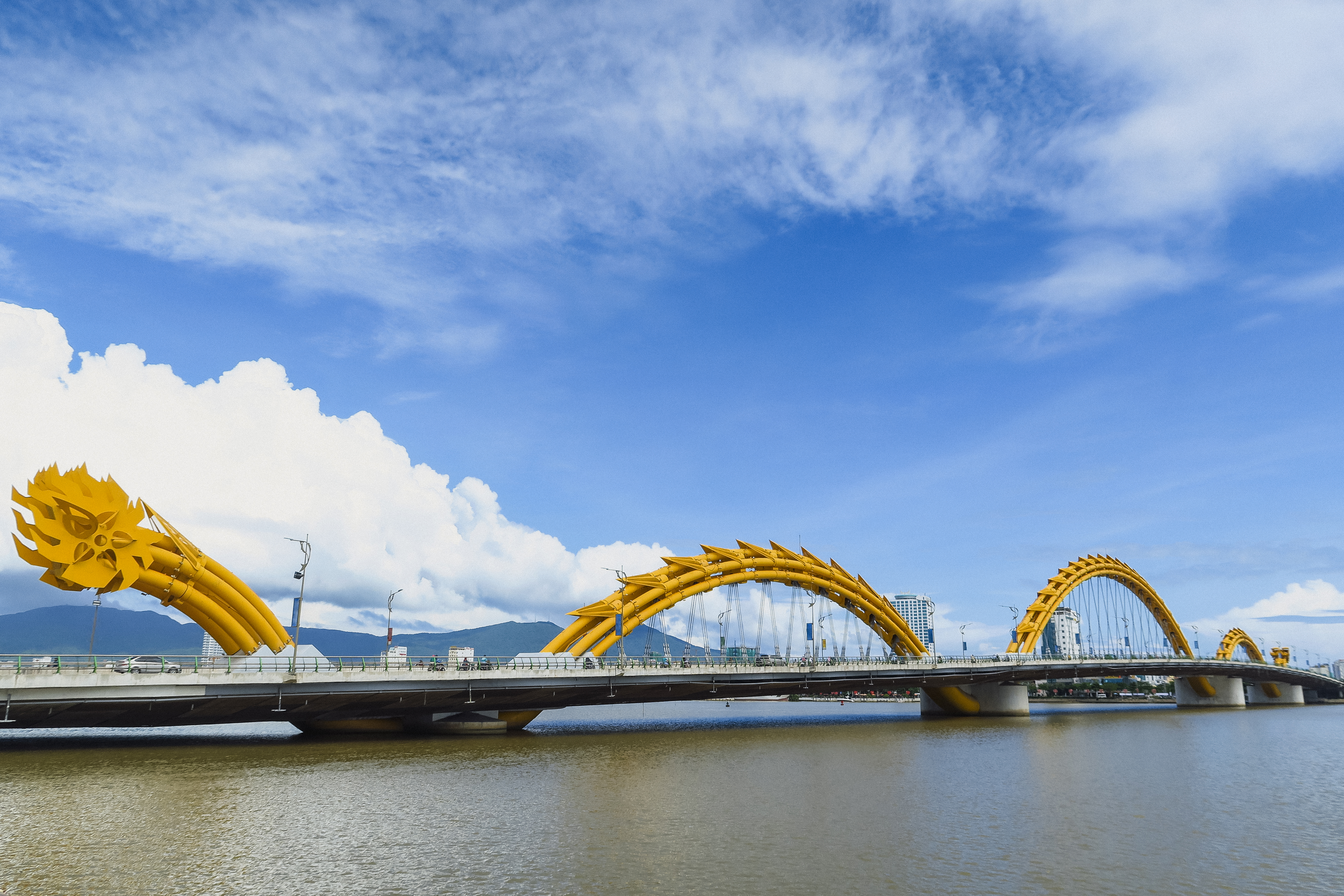 a bridge with a large yellow bridge over water