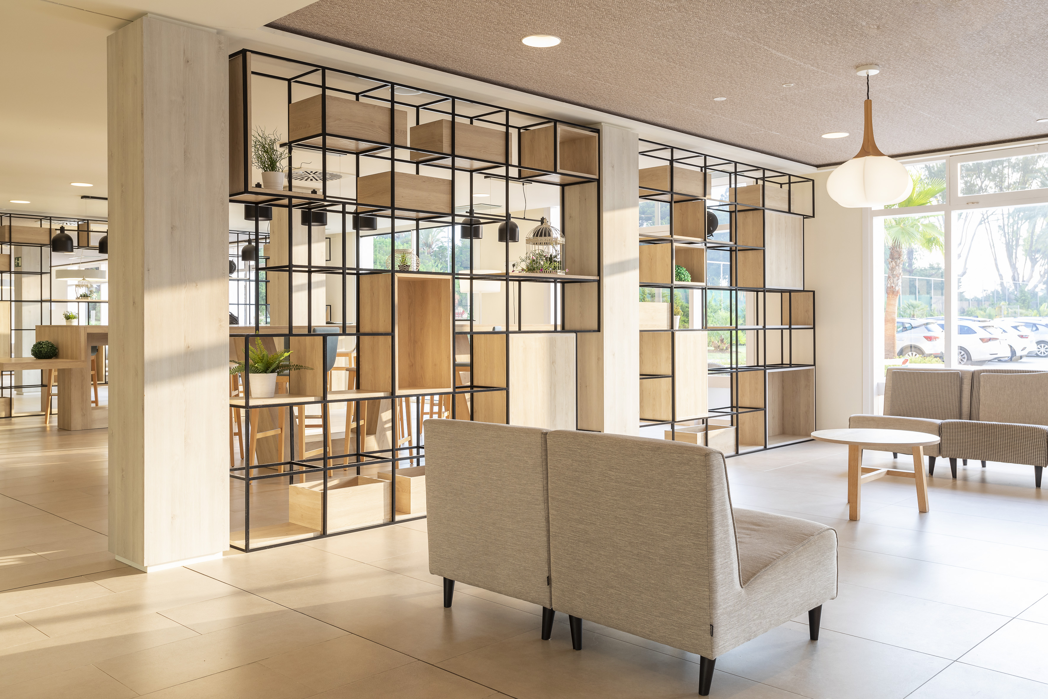 Contemporary lounge with modular shelving room divider, sofas, bright windows.