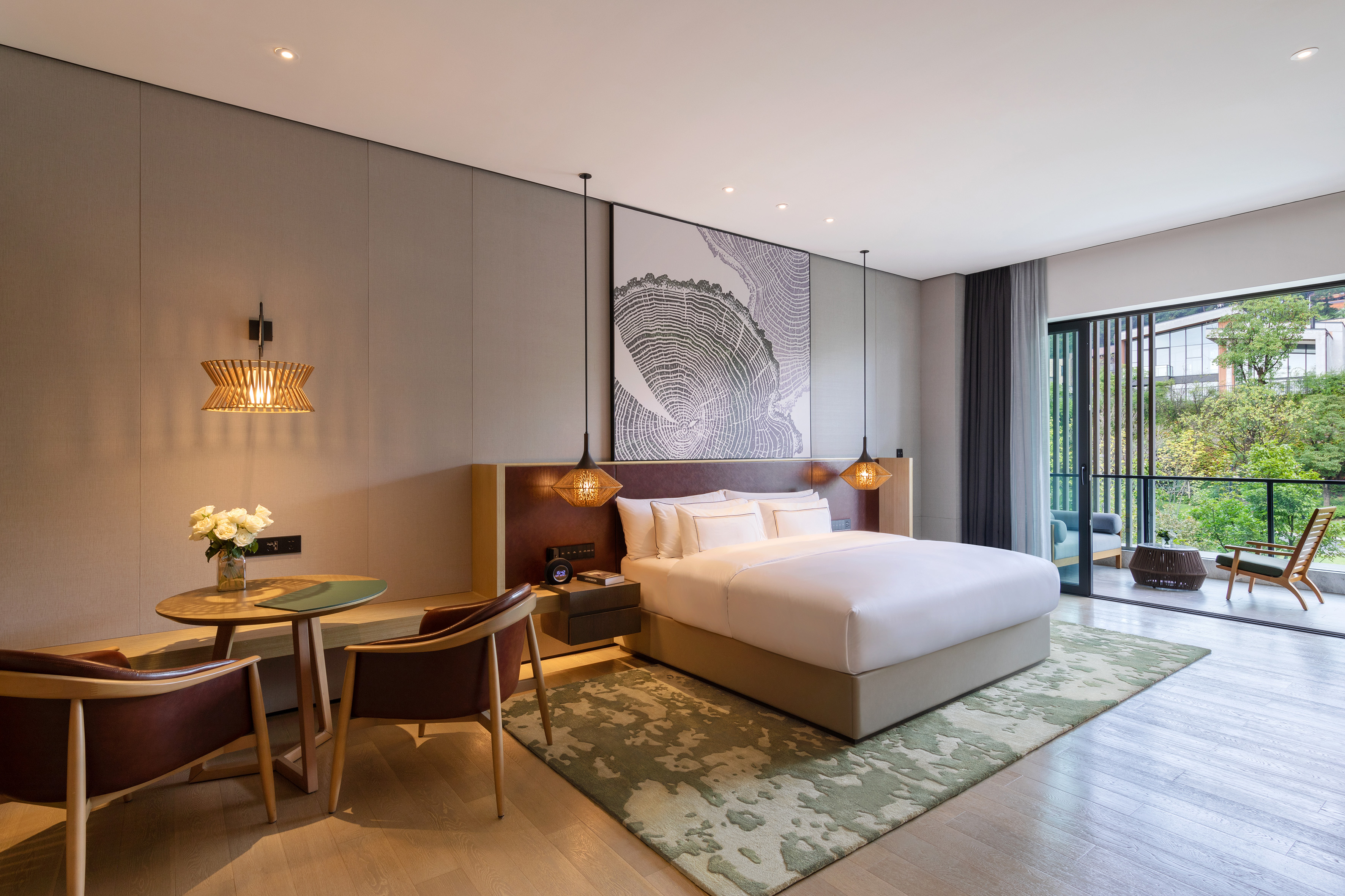 Modern luxury hotel room with king bed, balcony, and lush outdoor view.