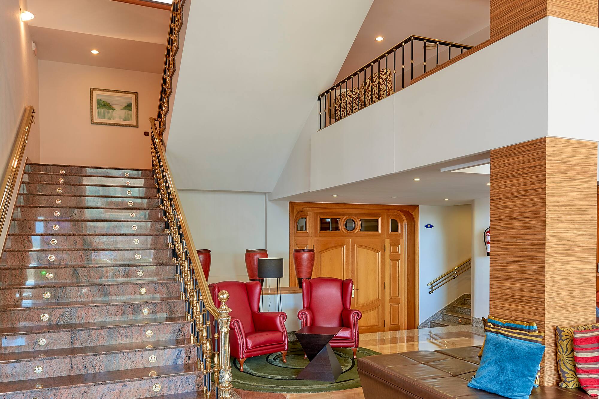 Luxury hotel lobby with marble stairs, red armchairs, and lounge area.