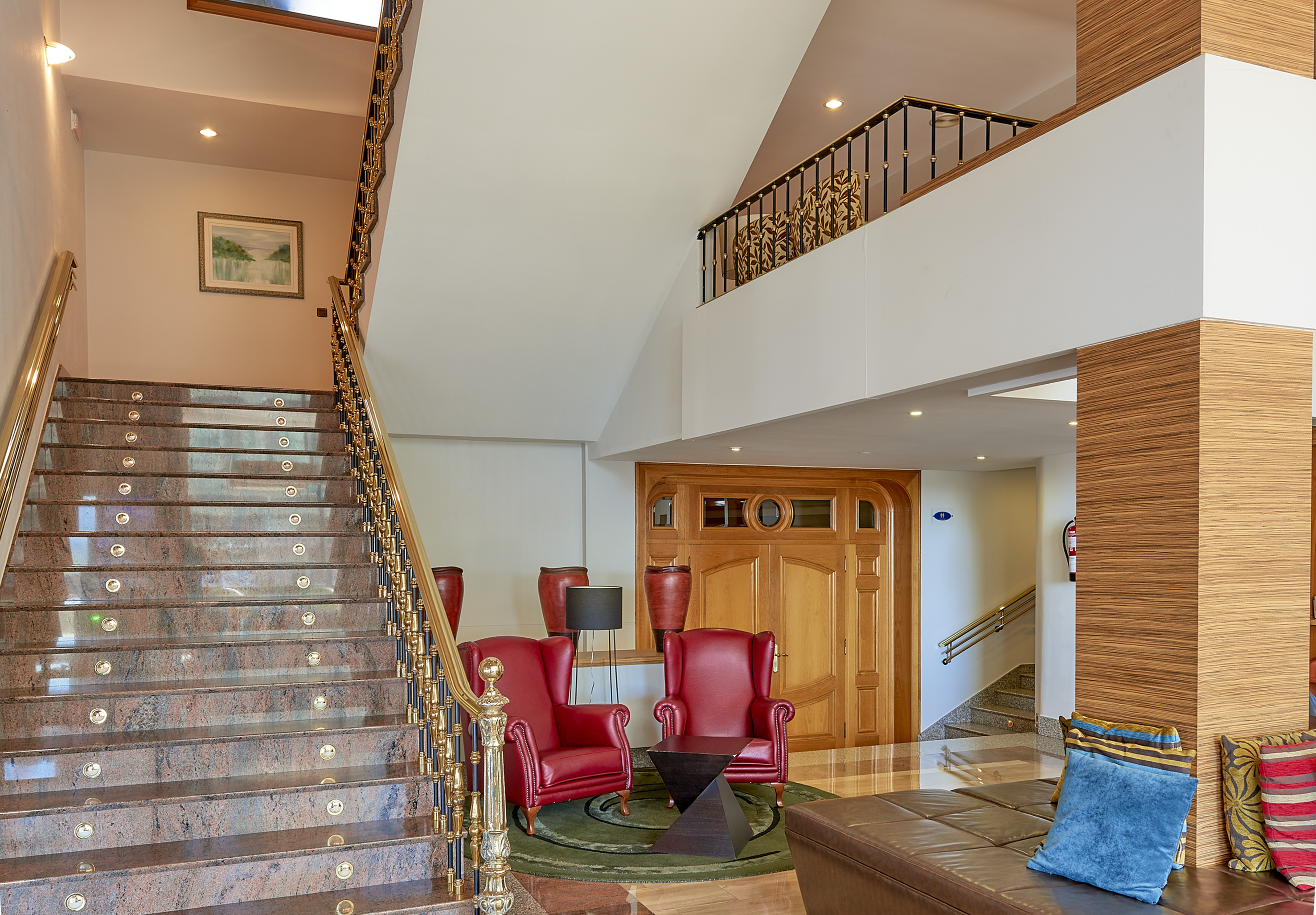 Luxury hotel lobby with marble stairs, red armchairs, and lounge area.