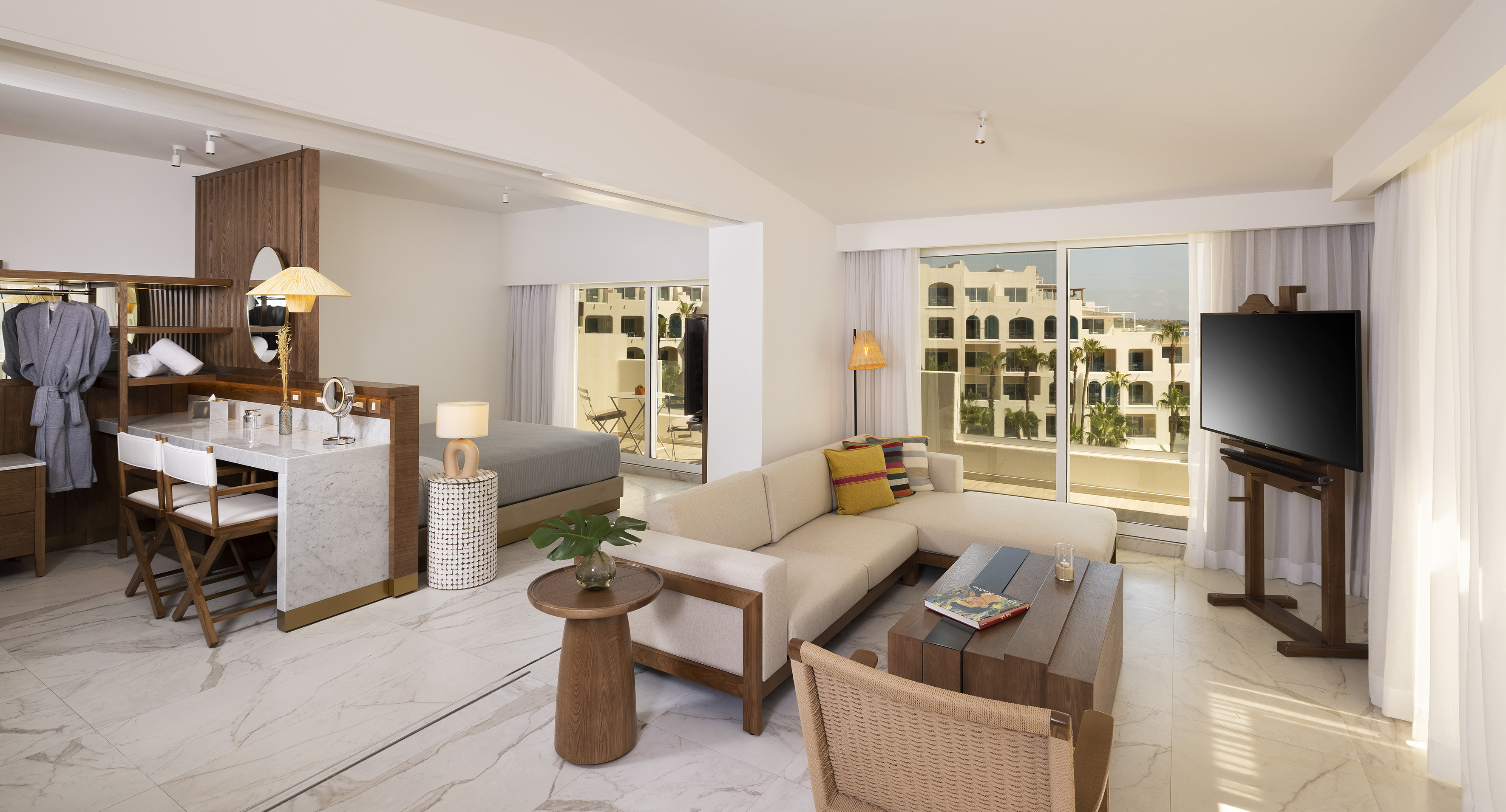 Modern hotel suite: open-plan living, bedroom, marble floors, resort balcony.