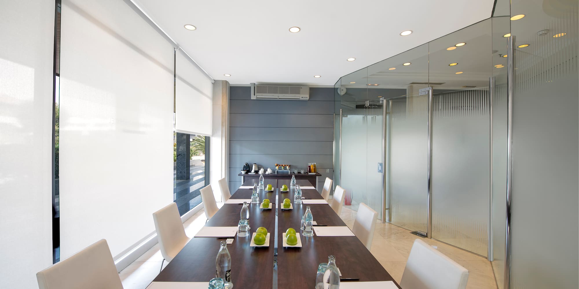a long table with white chairs and a glass wall