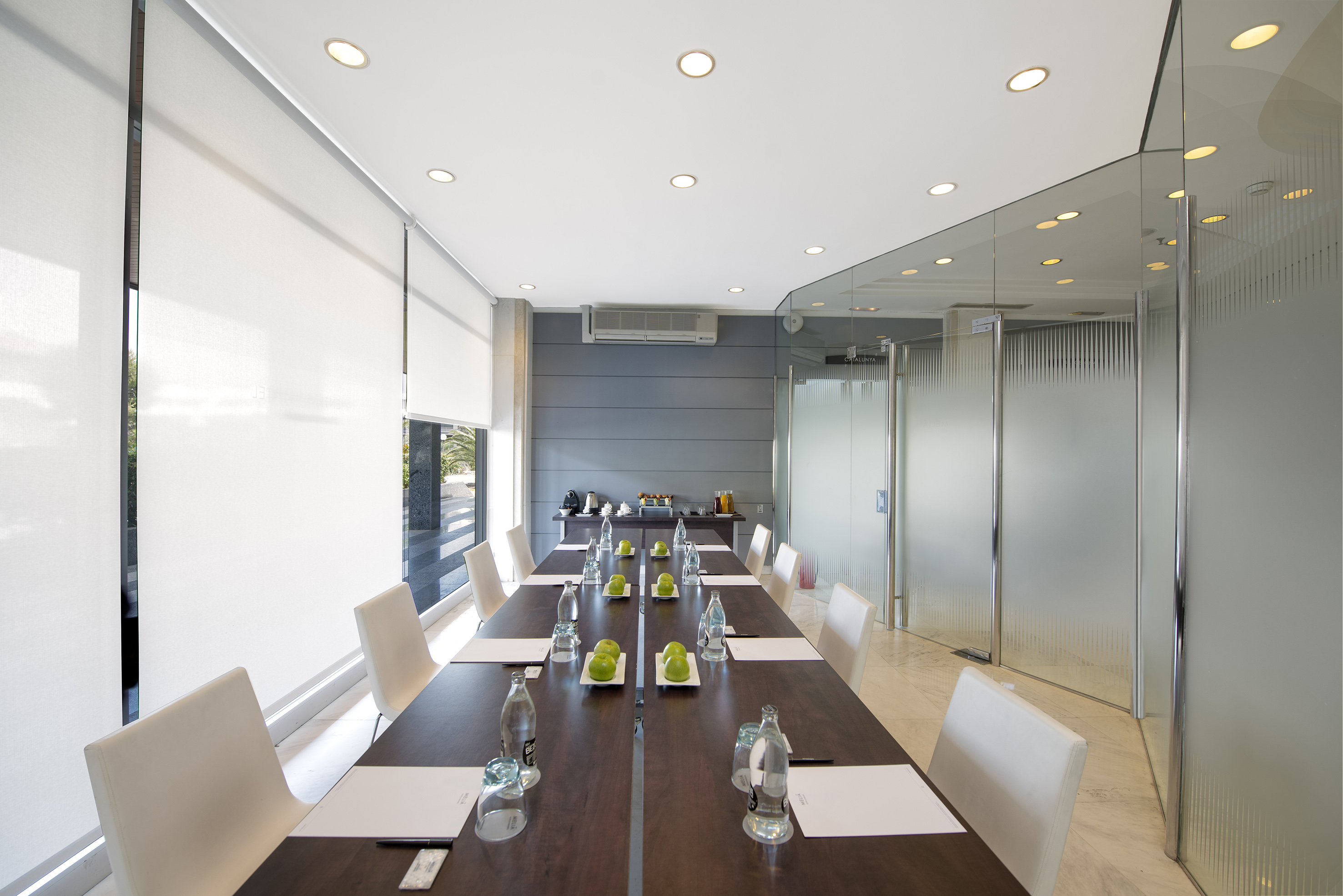 a long table with white chairs and a glass wall