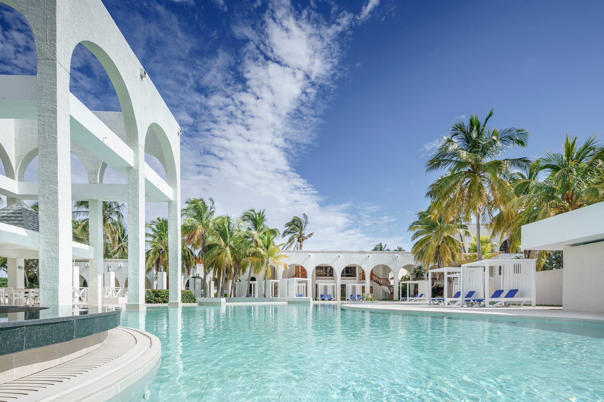 a pool with palm trees and a building
