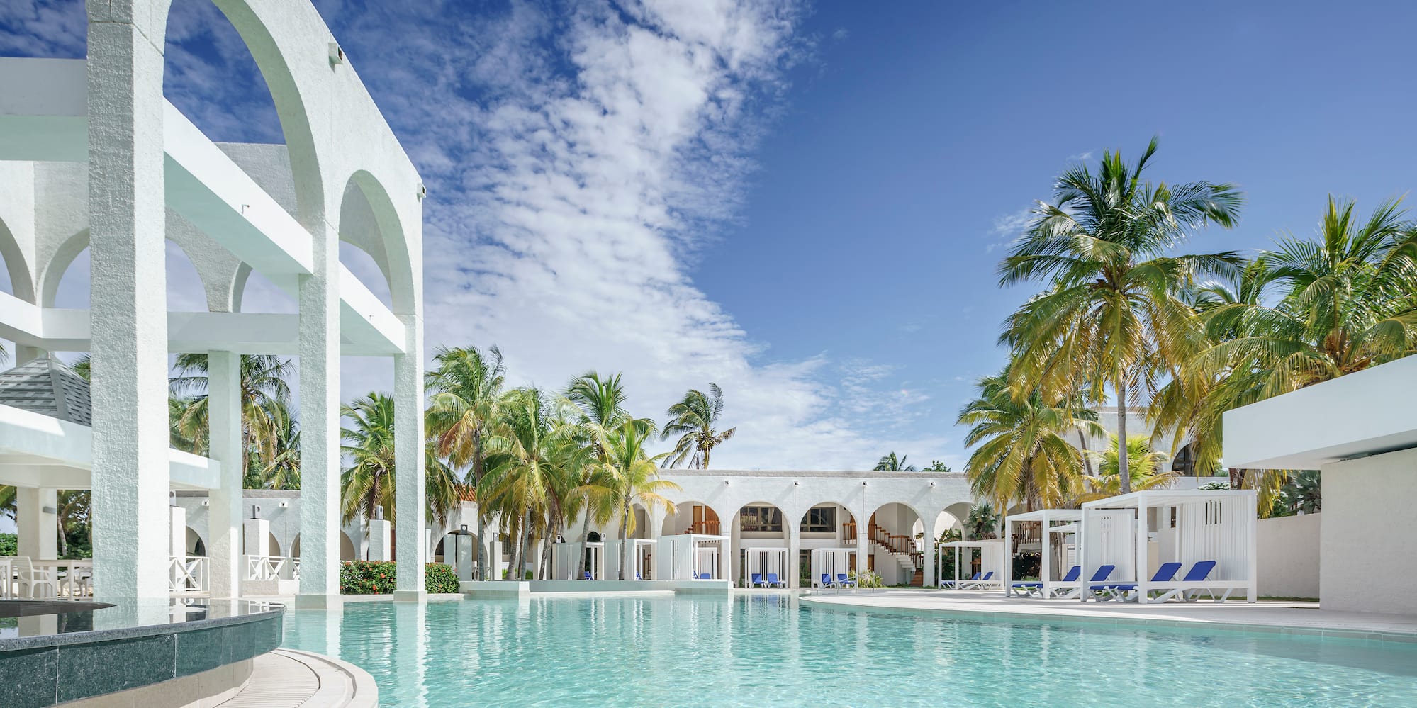 a pool with palm trees and a building