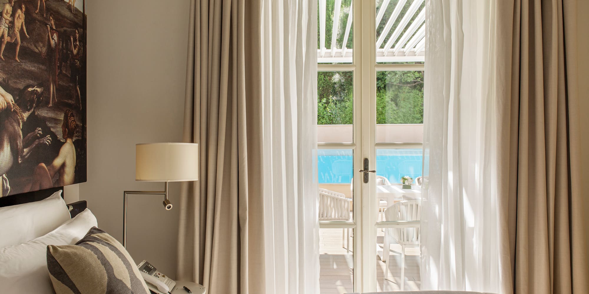 a bed with pillows and a lamp in a room with a pool outside