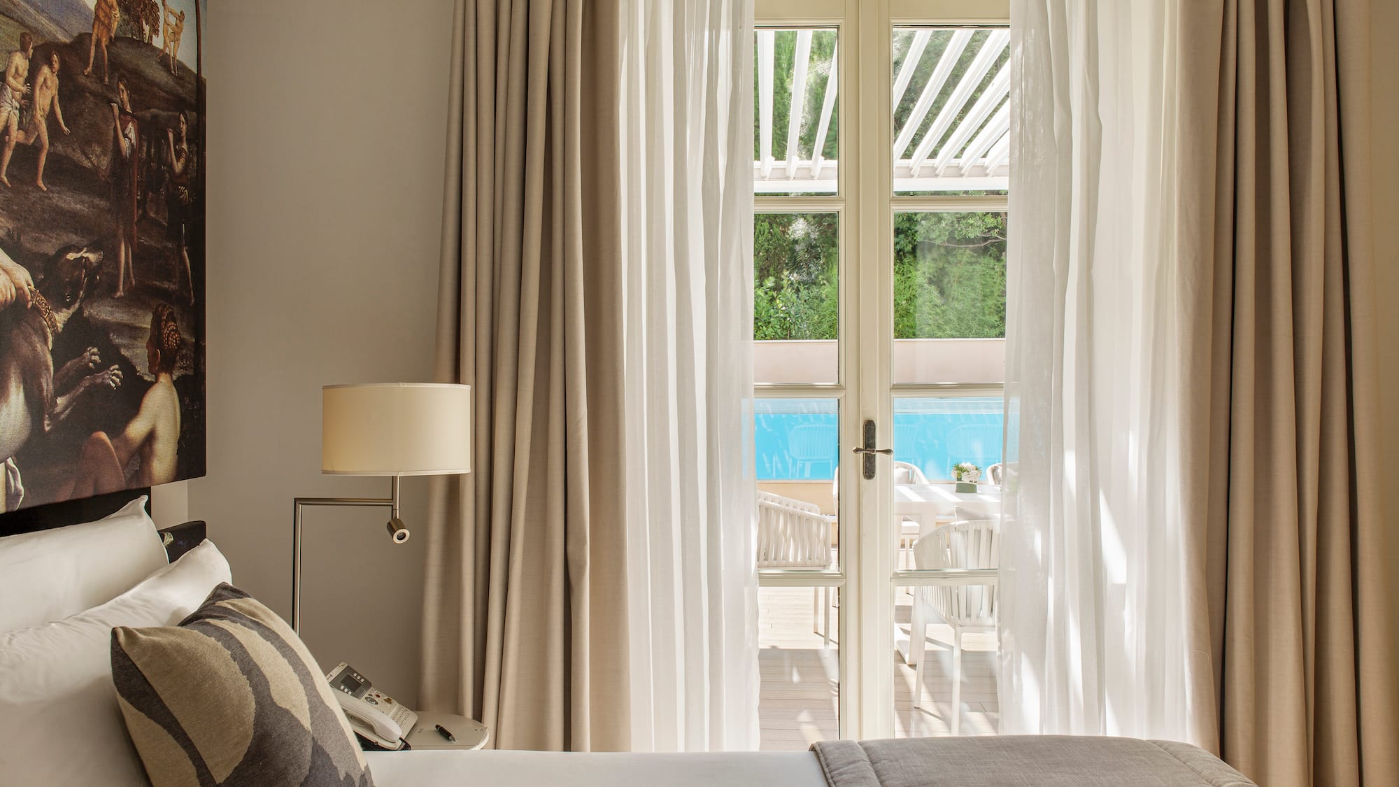 a bed with pillows and a lamp in a room with a pool outside