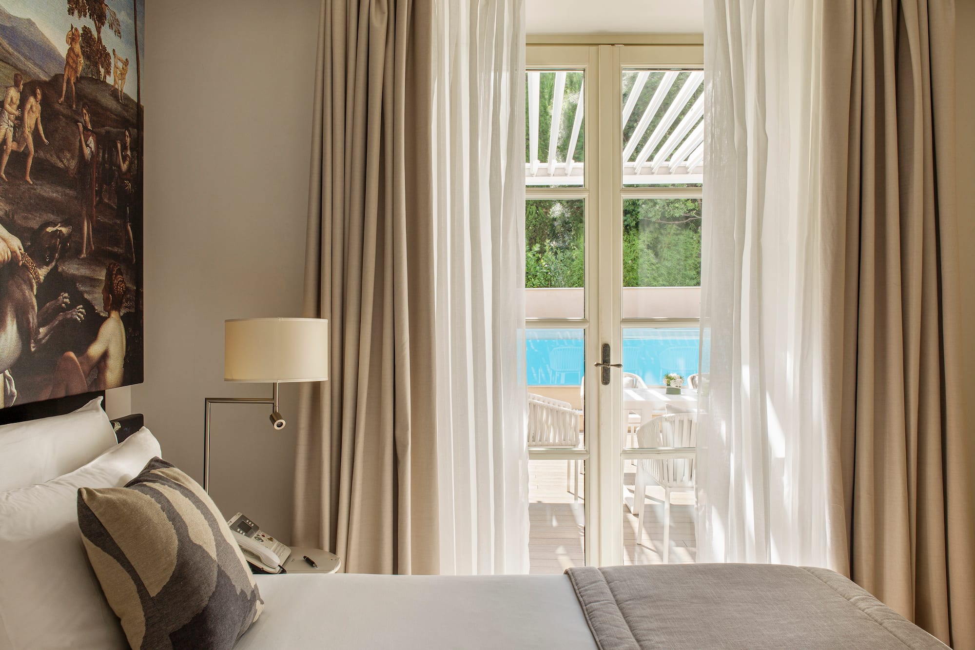 a bed with pillows and a lamp in a room with a pool outside