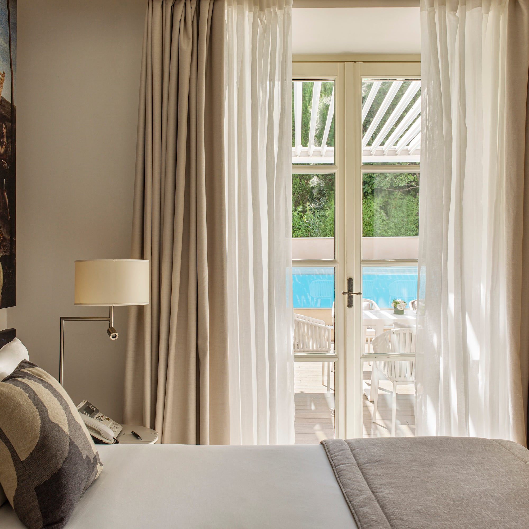 a bed with pillows and a lamp in a room with a pool outside