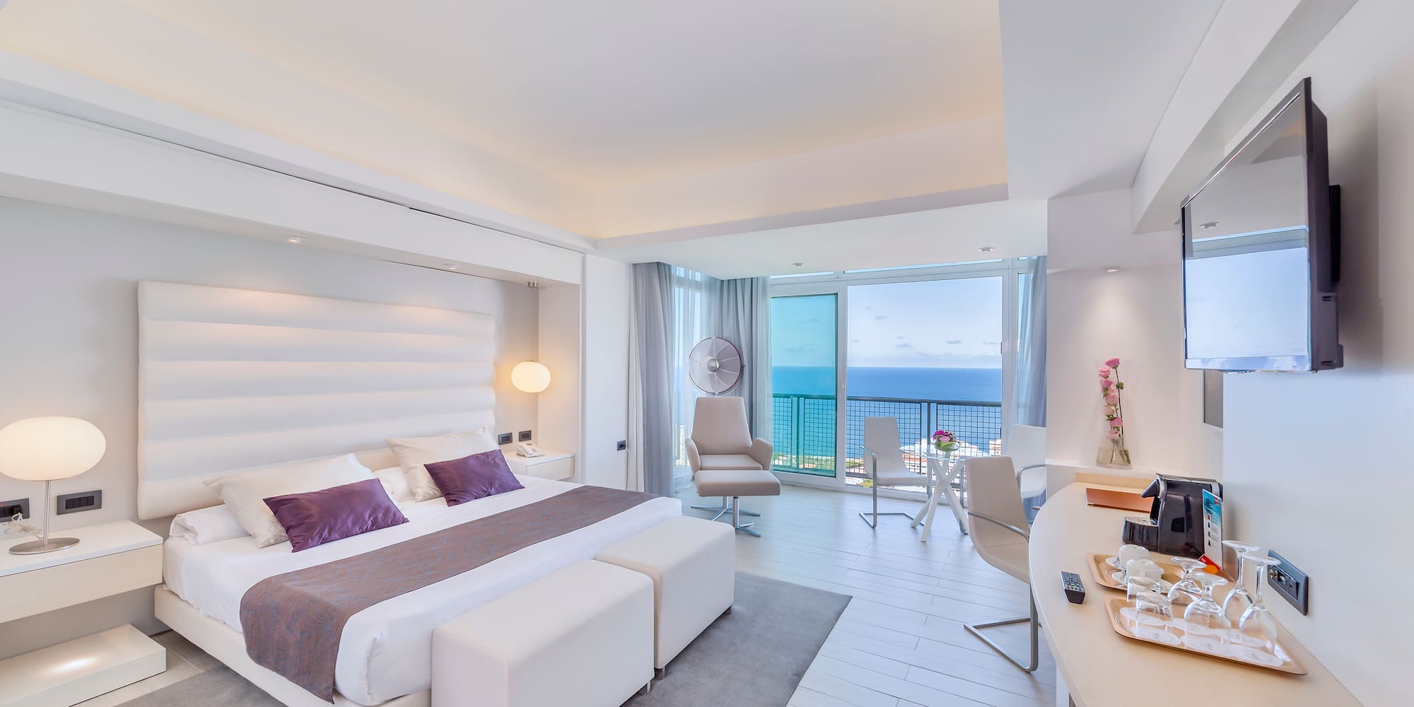 a bedroom with a large bed and a desk and chairs