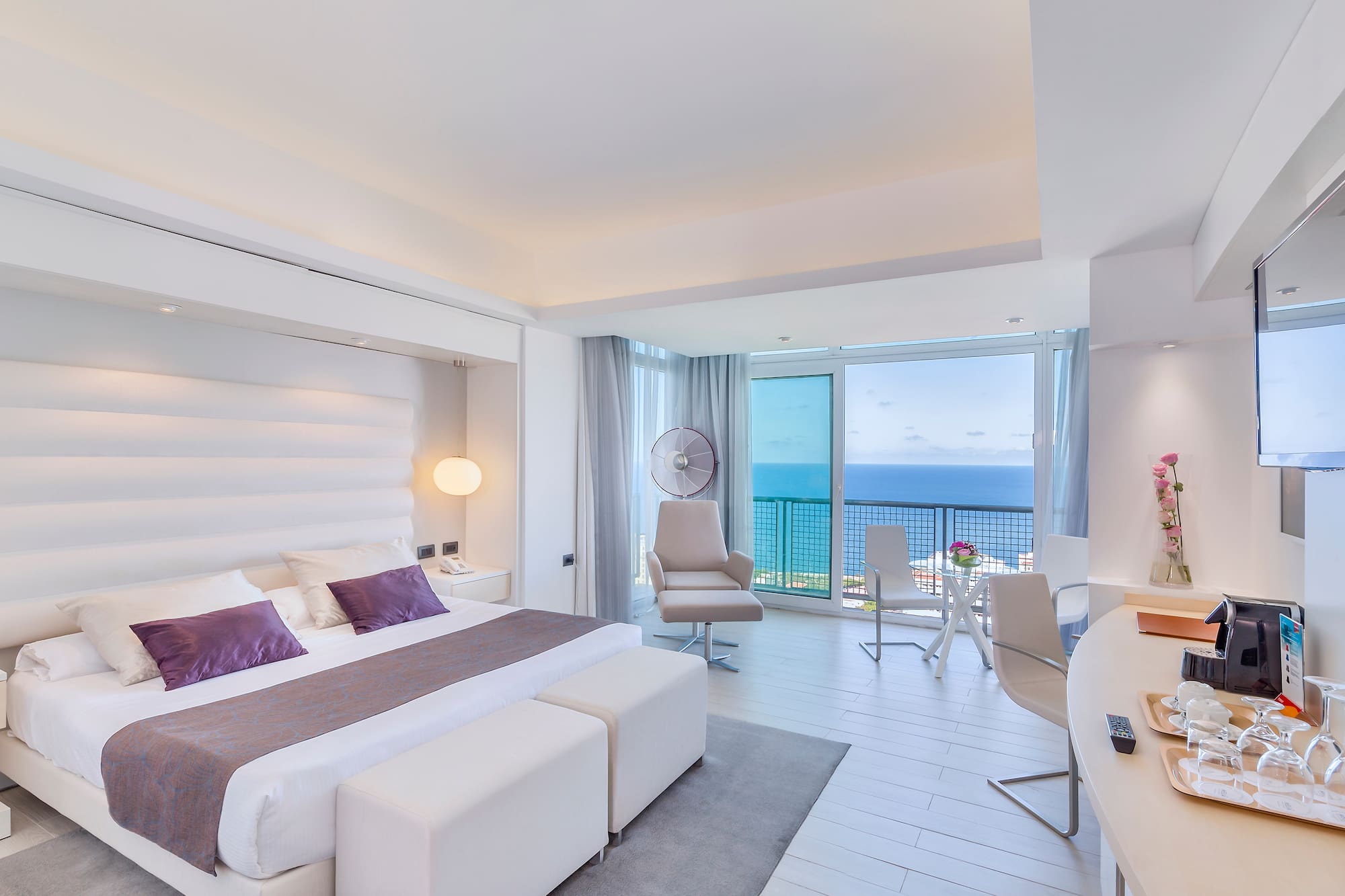 a bedroom with a large bed and a desk and chairs