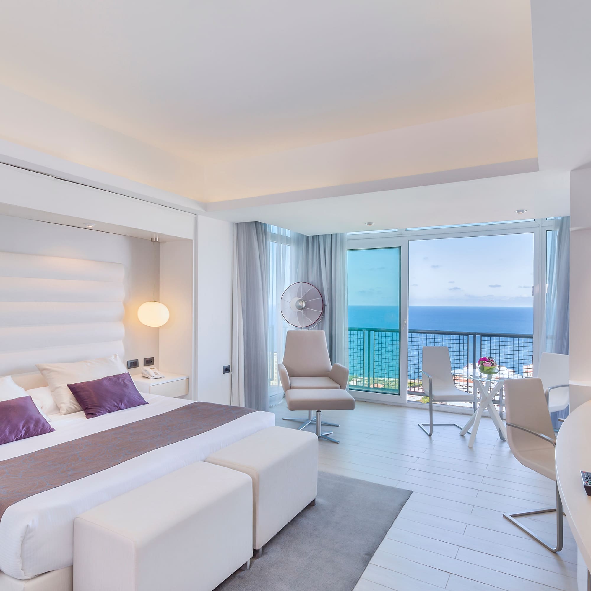 a bedroom with a large bed and a desk and chairs