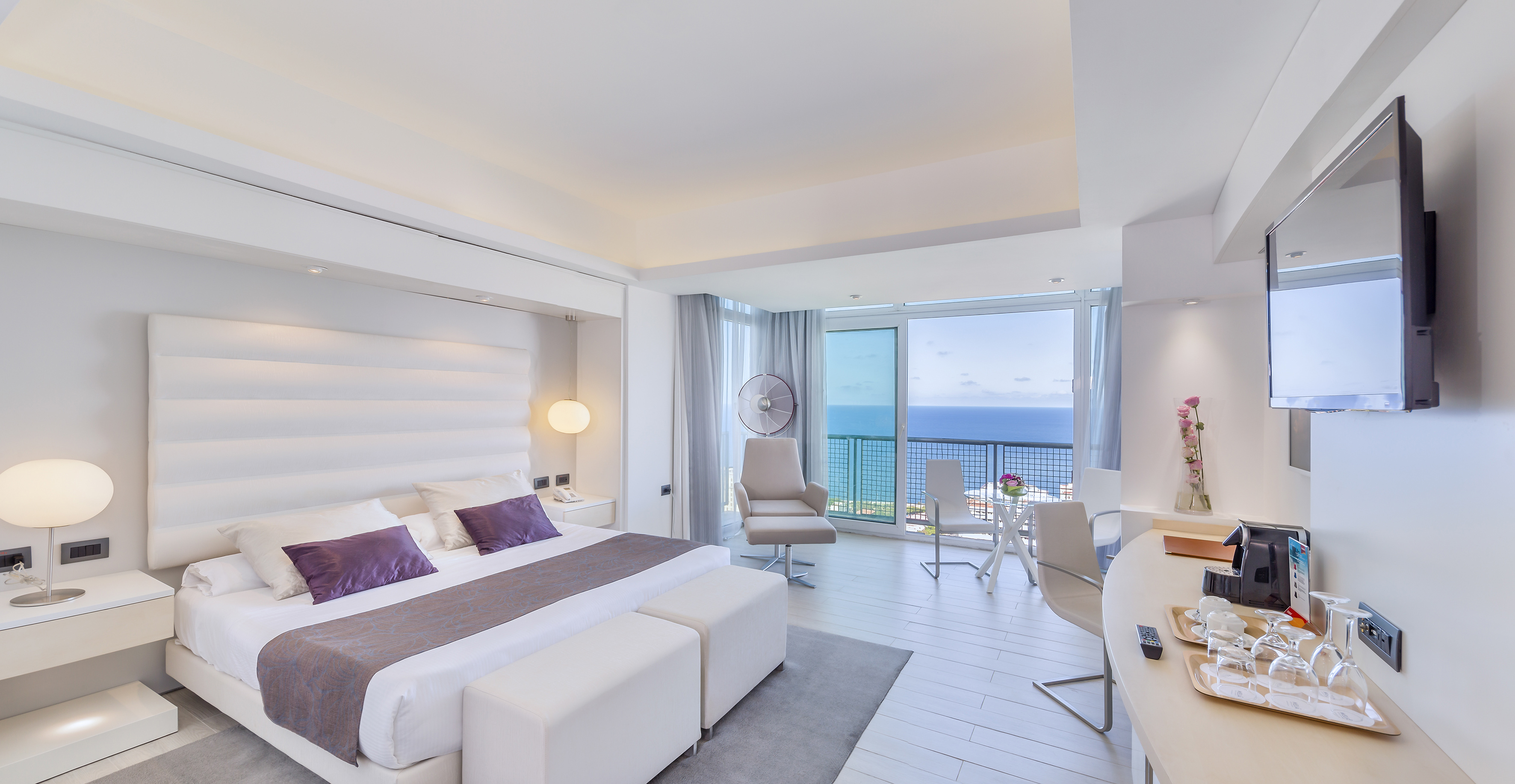 a bedroom with a large bed and a desk and chairs