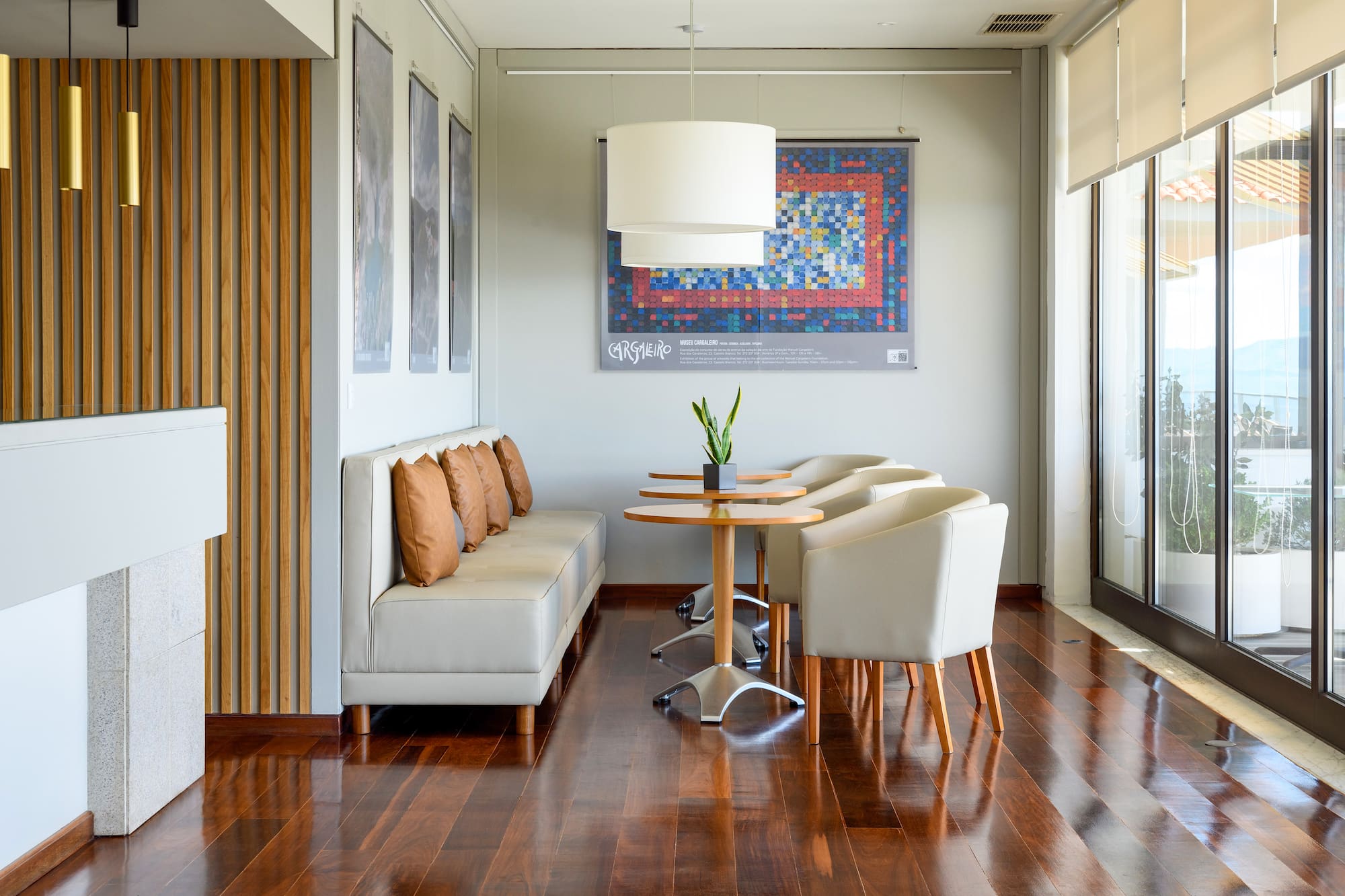 Modern lounge with beige seating, wood tables, and dark hardwood floor.